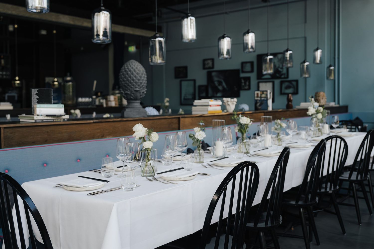 An elegant wedding reception table setting with white linens and pendant lighting.