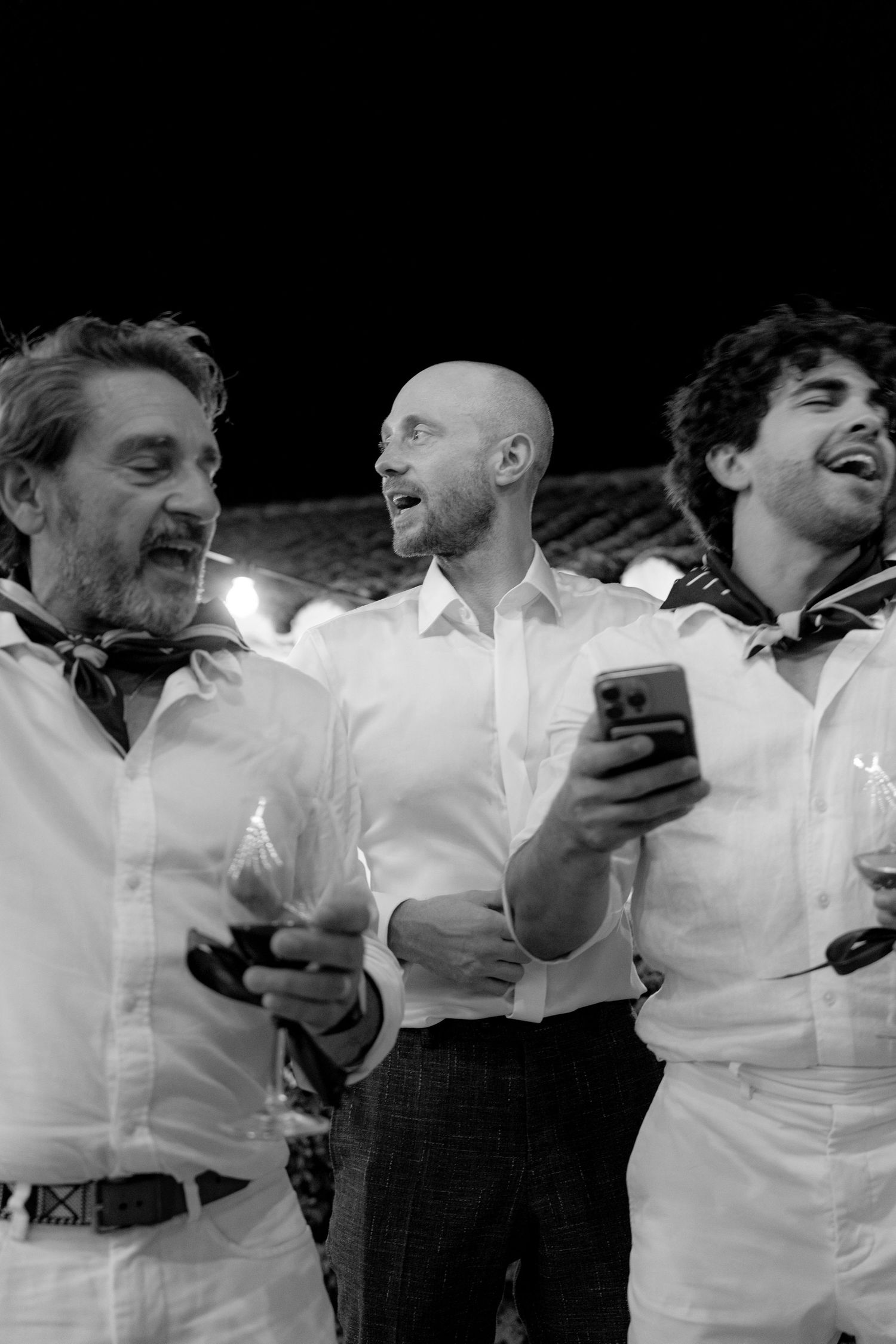 Black and white photo of guests laughing and celebrating at a wedding reception.