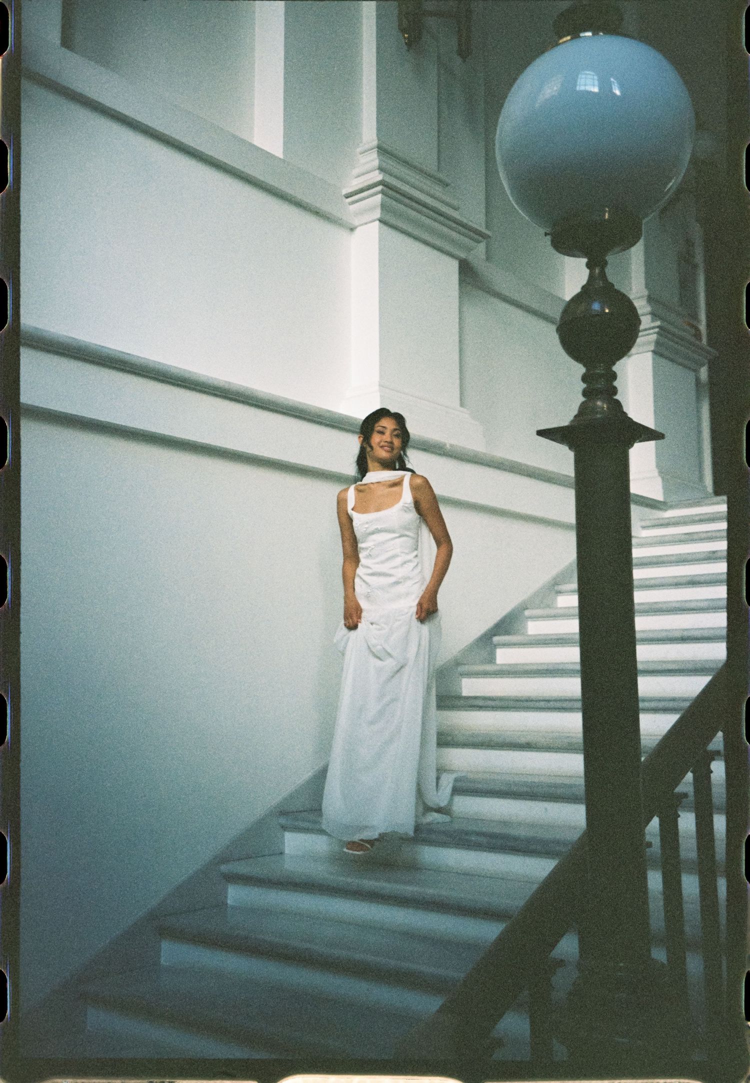 Artistic photos of someone in white dress descending stairs in moody lighting.