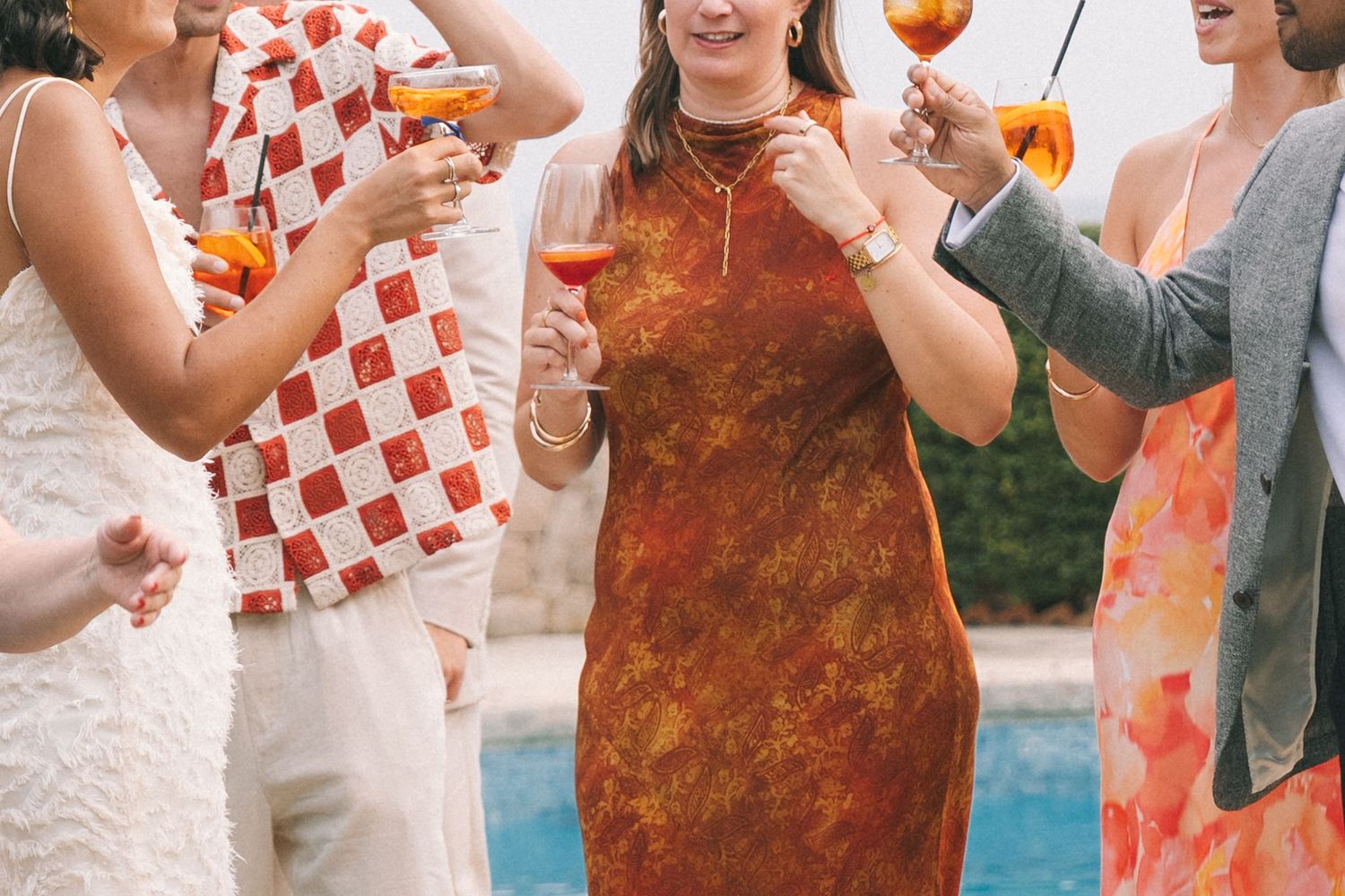 Wedding guests in red and white checkered outfits celebrate joyfully at an outdoor reception.