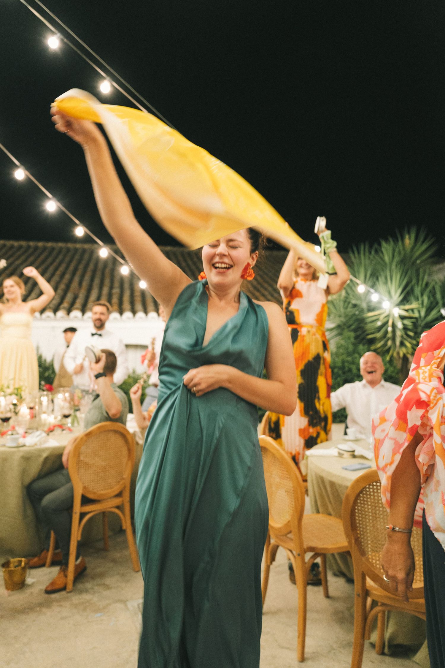 Guests in formal attire dancing and celebrating at an outdoor evening reception.