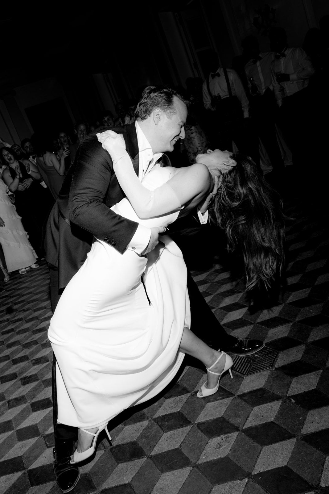 Black and white photo of a bride and groom sharing a romantic dip dance at their wedding reception.