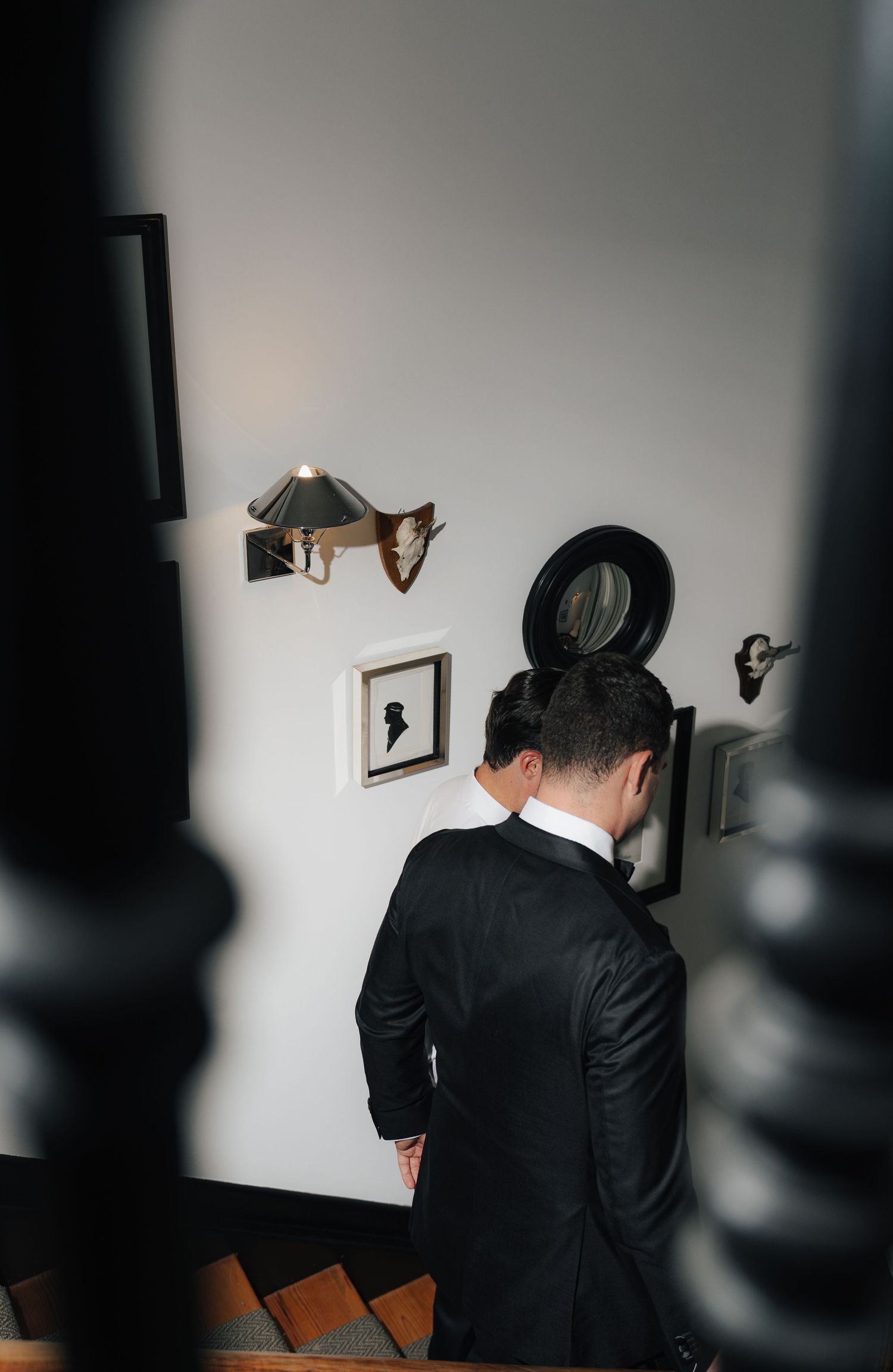 Person in dark suit looking at framed artwork on wall.