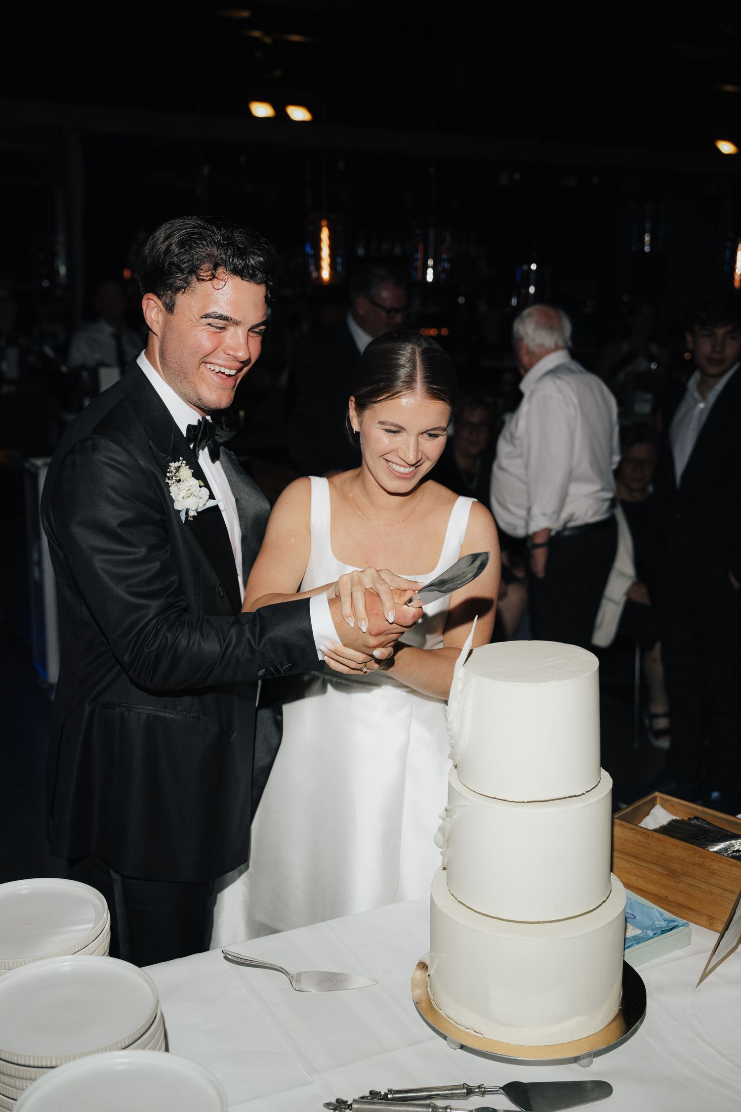 Newlyweds cutting their elegant white tiered wedding cake together.