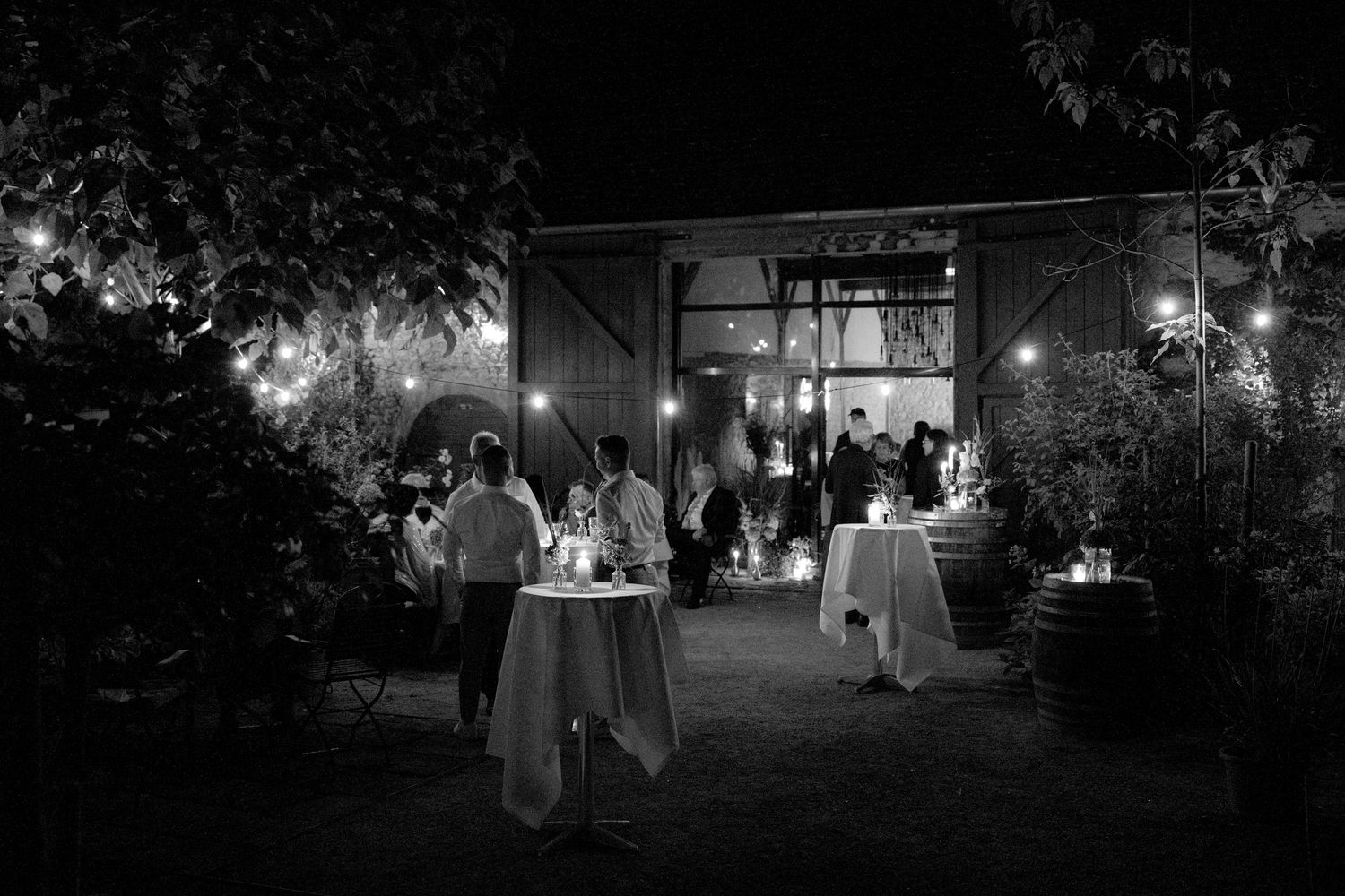 Nighttime outdoor venue with pathway lit by string lights and lanterns.