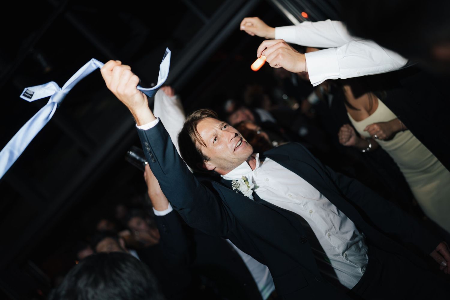 People dancing and celebrating at a nighttime wedding reception.