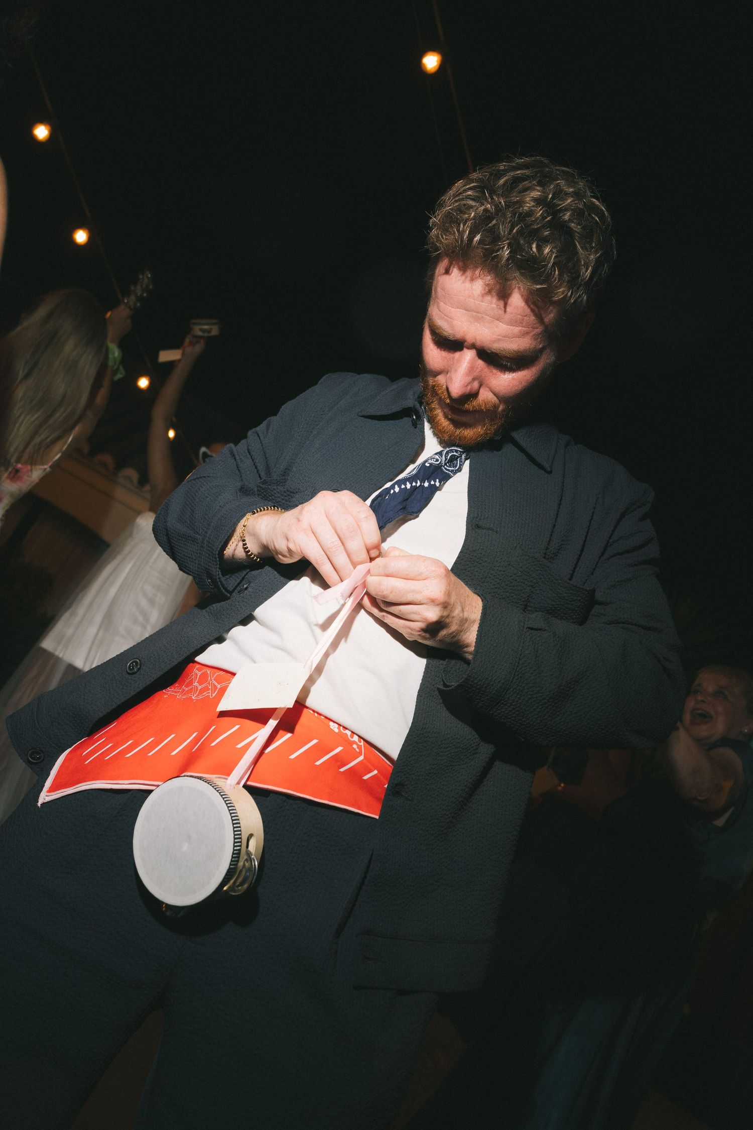 Person in dark clothing tearing open their dress shirt at a party.