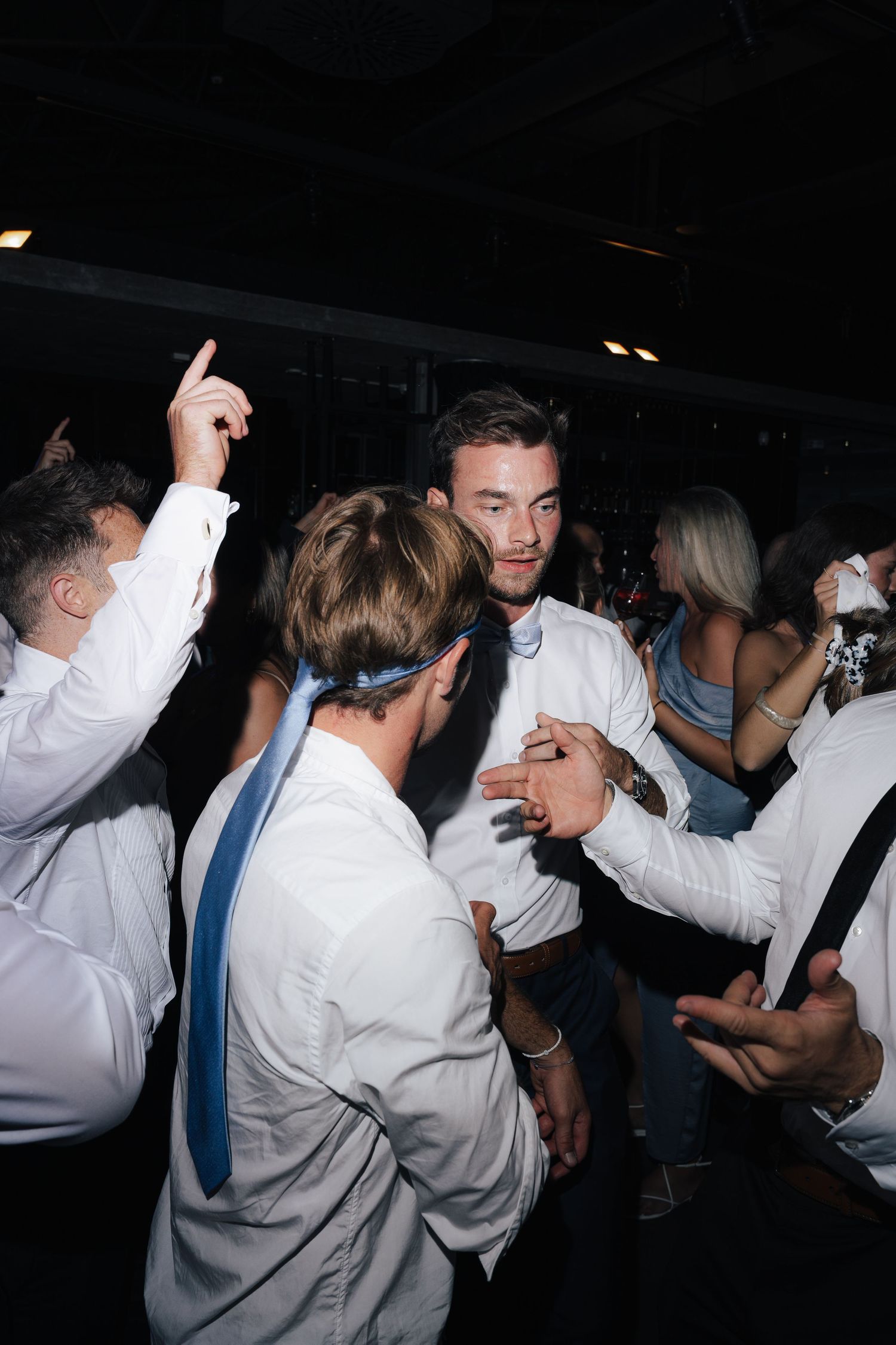 Group of people in white shirts dancing and celebrating at a party.