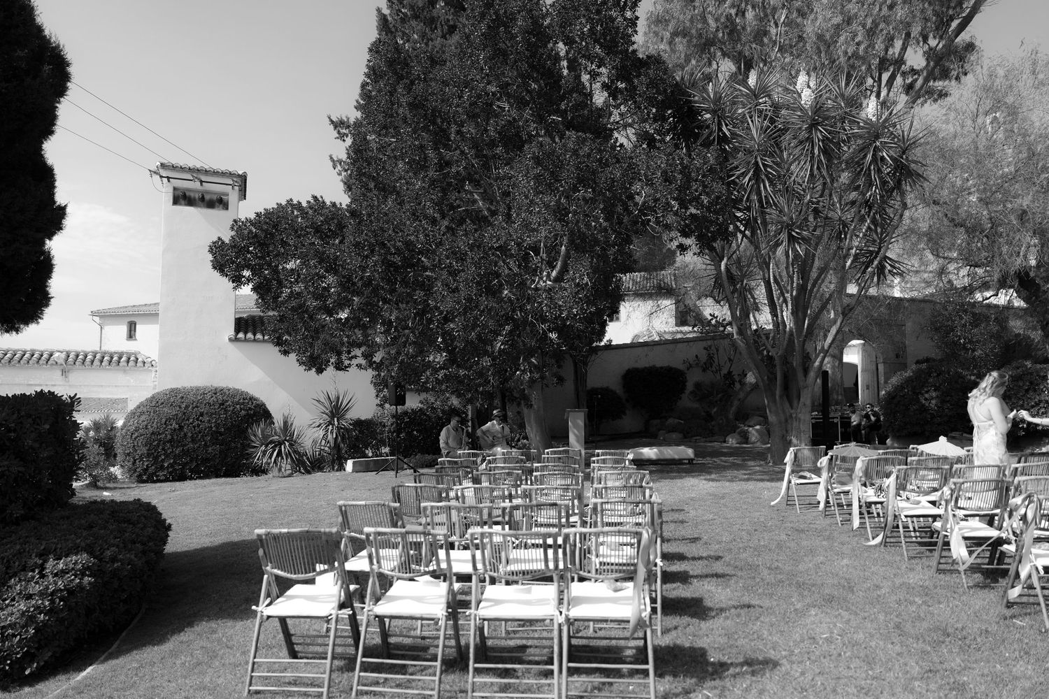 Black and white image of empty wooden chairs set up for an outdoor event.