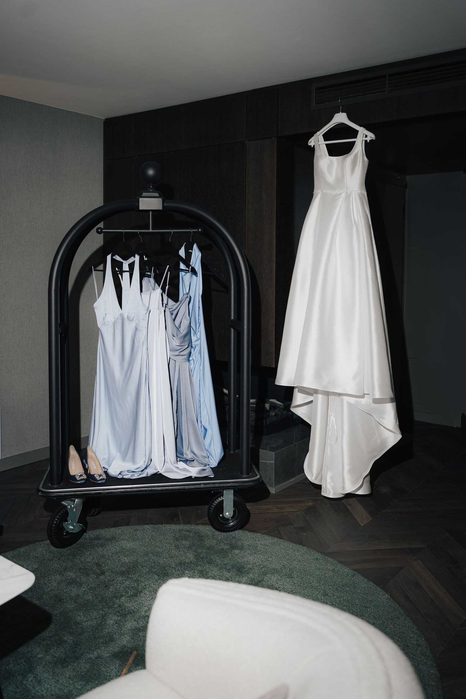 Wedding dresses and formal attire displayed on black clothing racks in a room with dark walls.