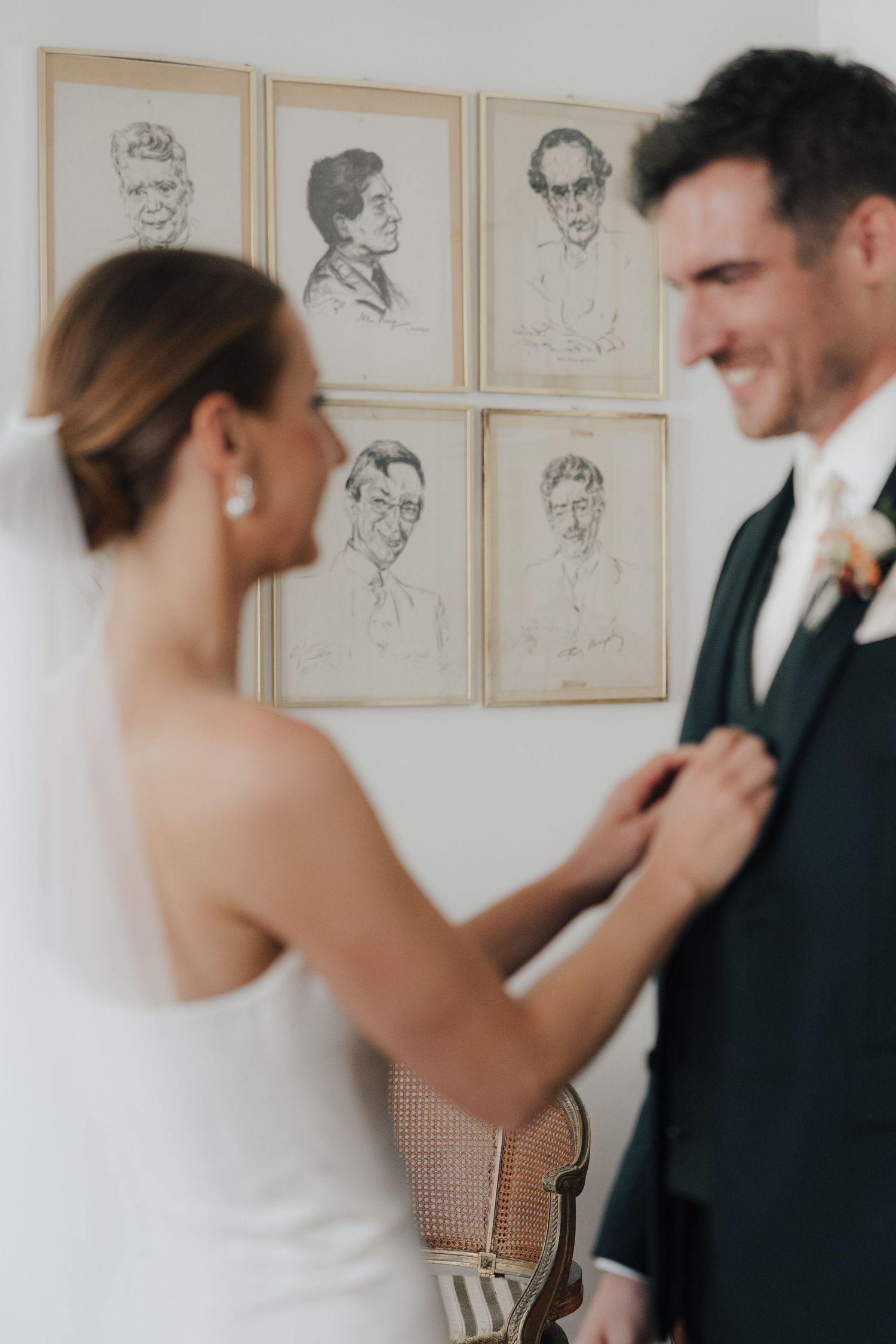 Wedding preparation scene with framed portraits on the wall in the background.