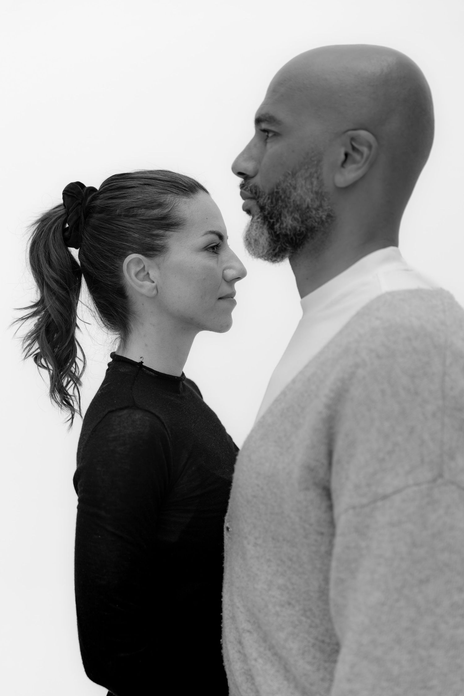 Black and white portrait of a man and woman facing each other in profile against a white background.