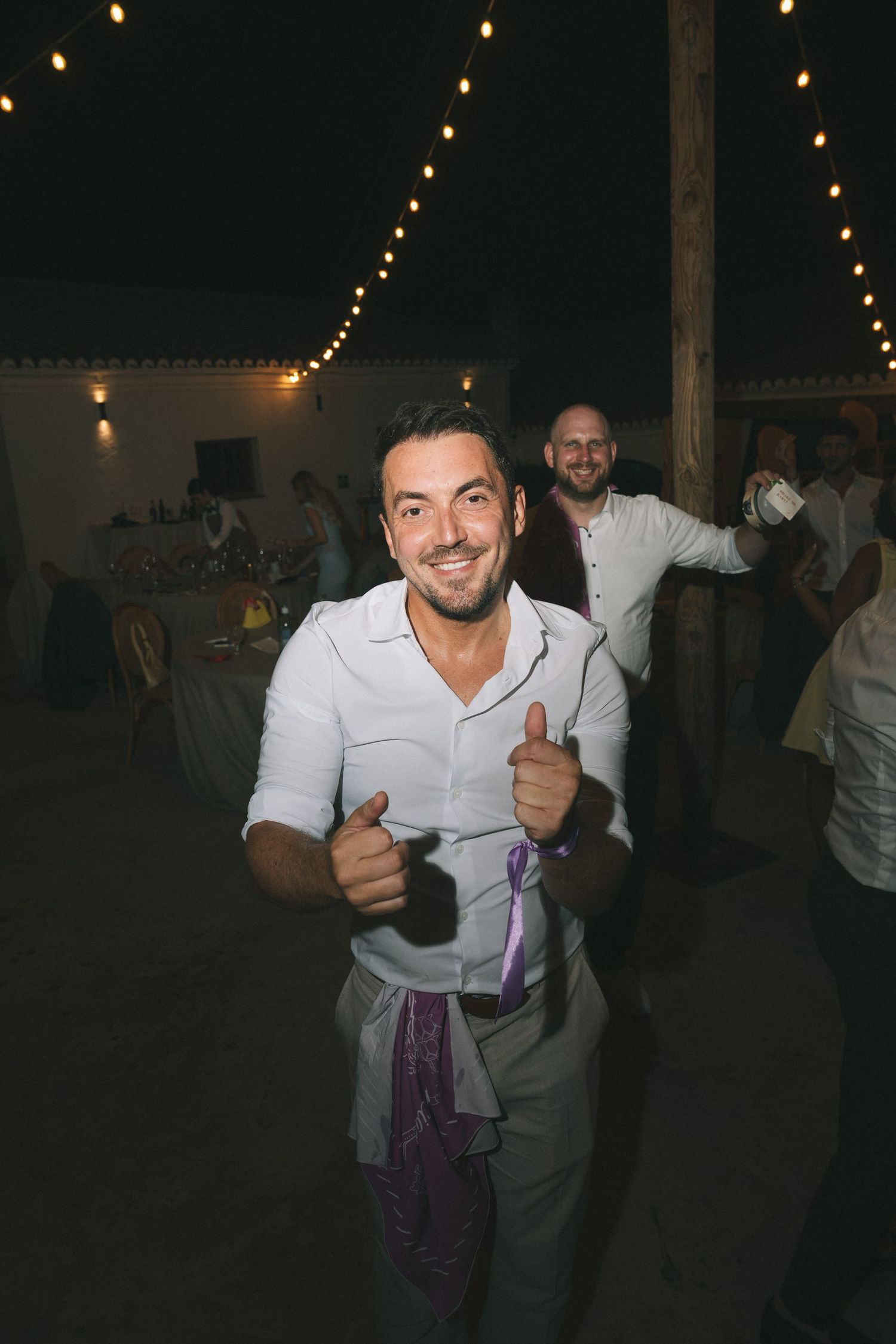 People dancing and celebrating at a dimly lit indoor reception.