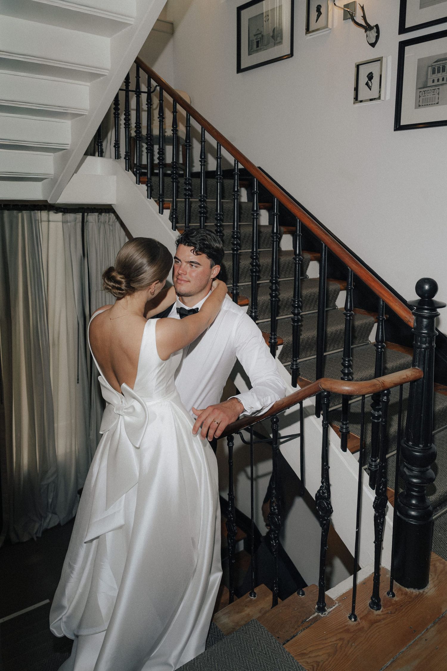 Wedding party members in white attire posing playfully on an elegant staircase.