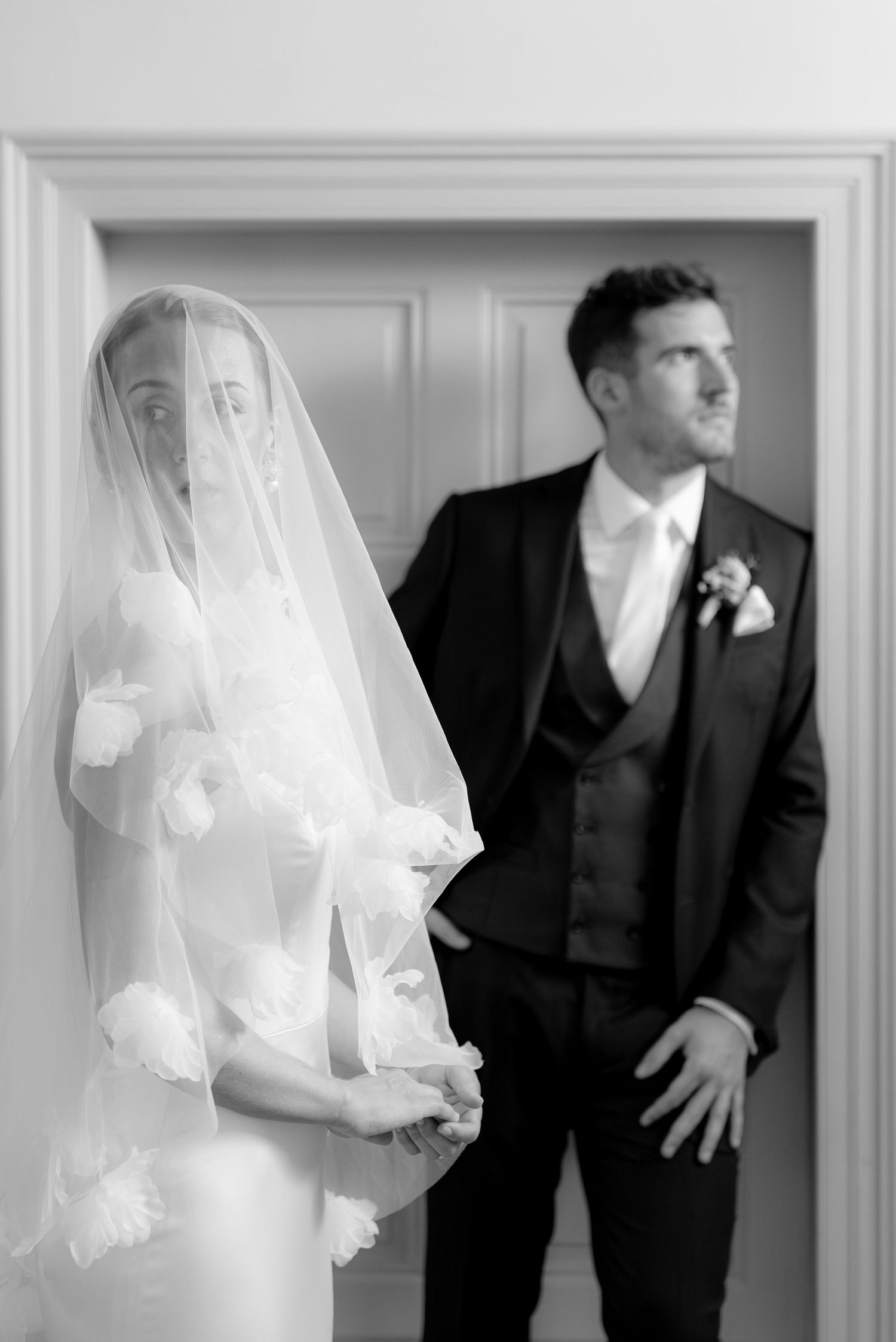 Black and white wedding photos showing playful moments in a doorway.