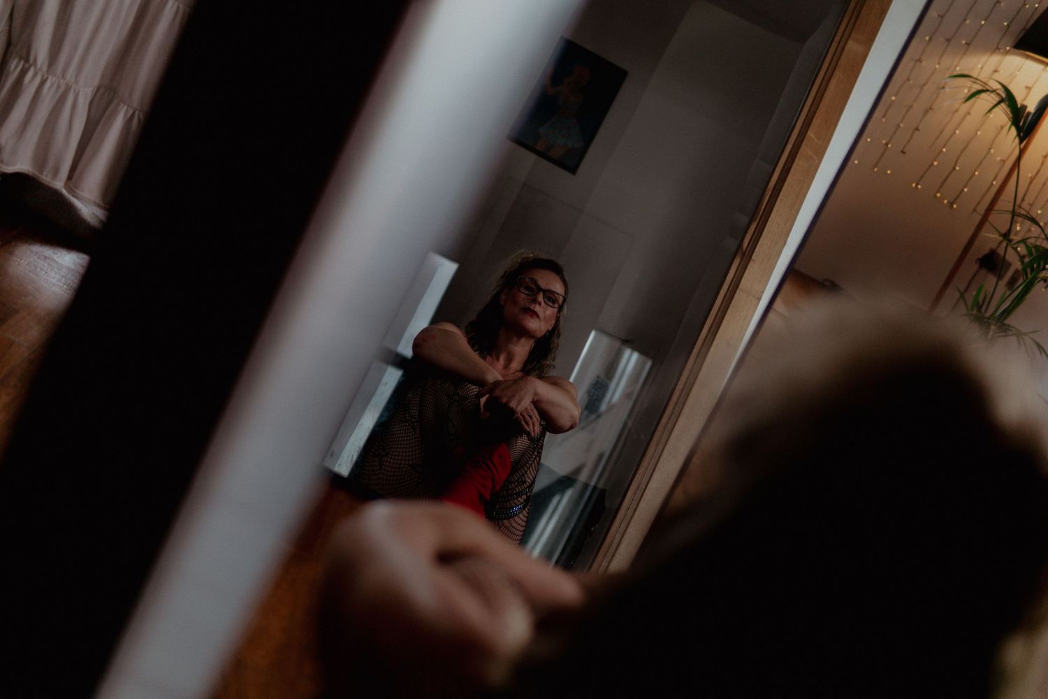 Woman in red and black outfit reflected in a dark mirror. Liverpool boudoir photography