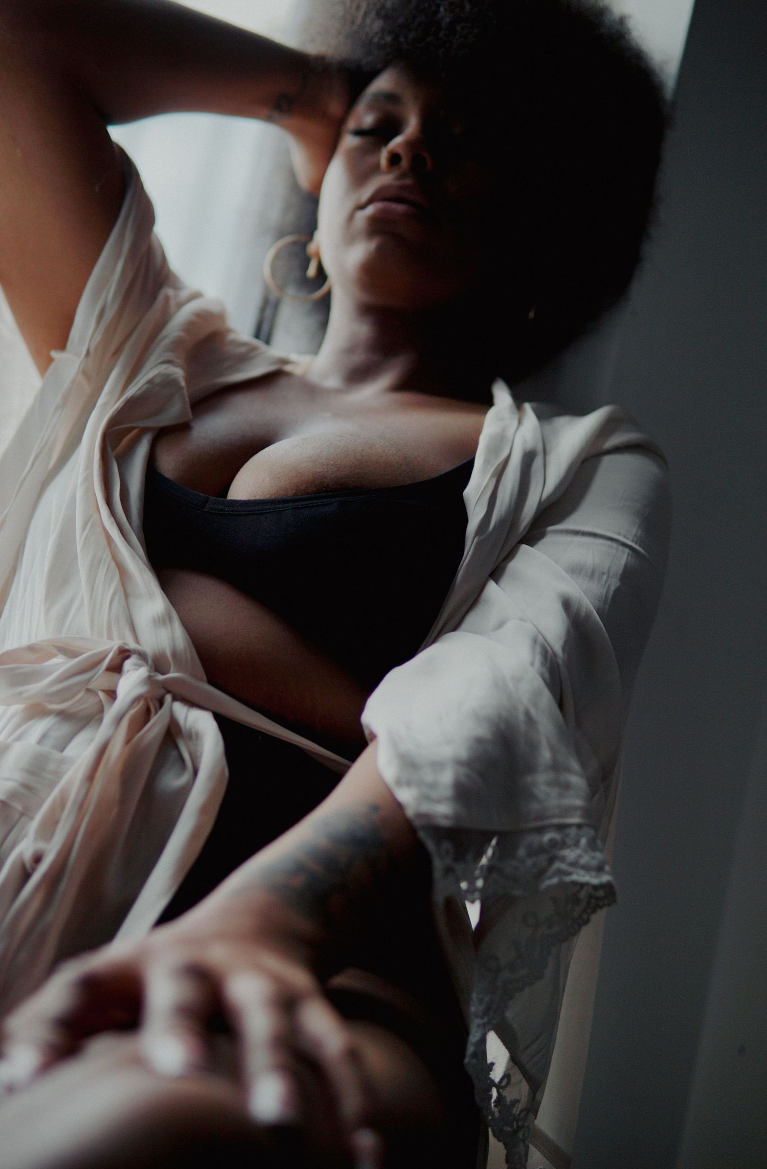 Woman with afro in black underwear and white robe sitting on window seal  Boudoir photography UK Liverpool