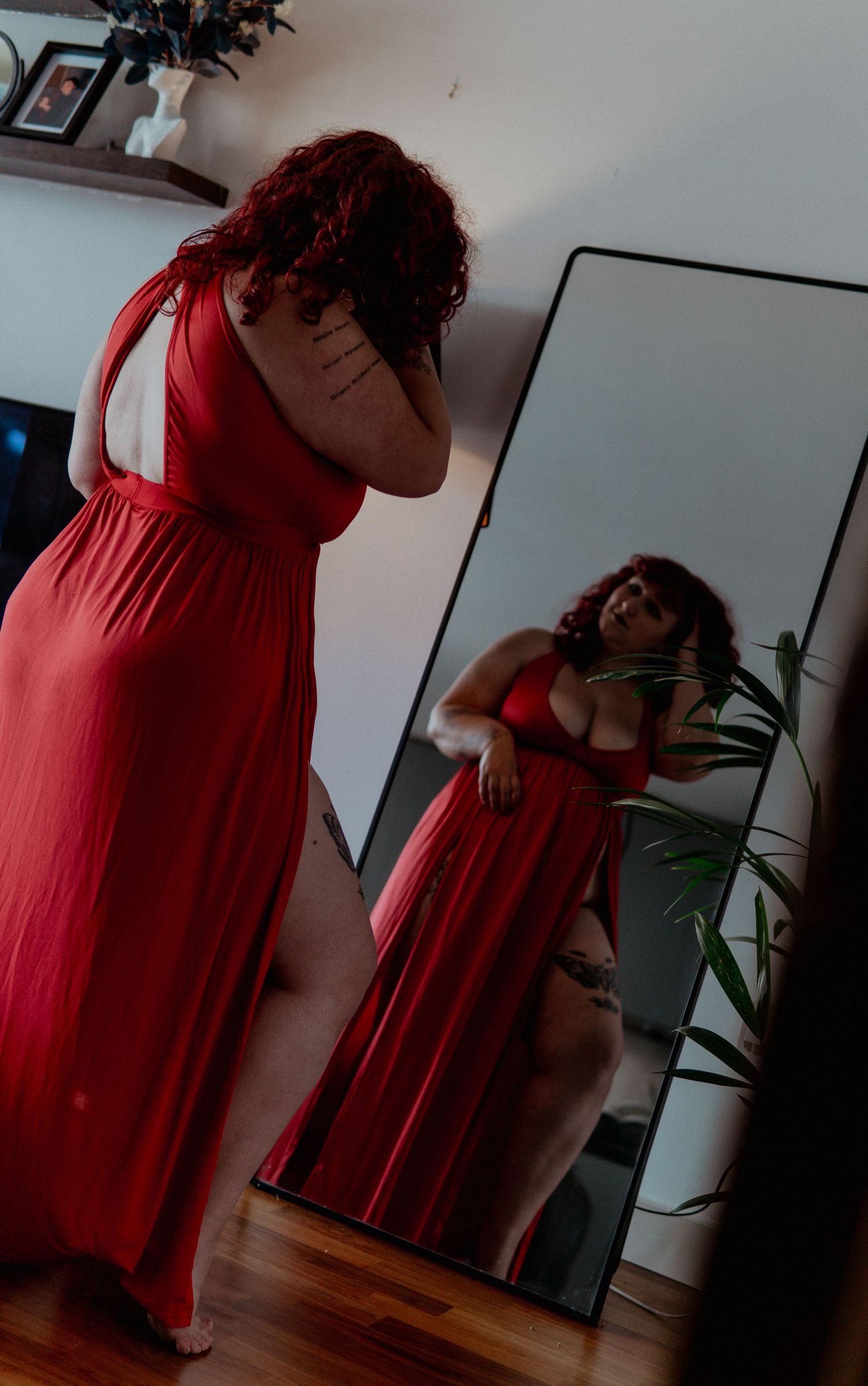 Ginger woman in red long dress staying in front of mirror looking at her reflection Boudoir photography UK Liverpool