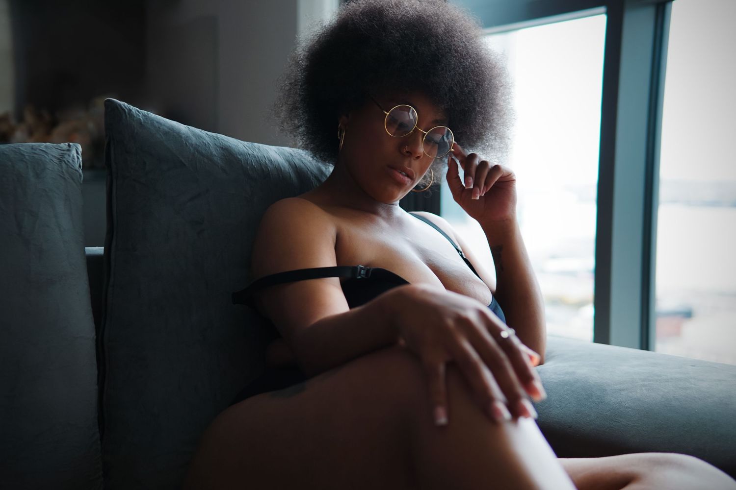 Woman confidently sitting in round glasses, Boudoir photography UK Liverpool