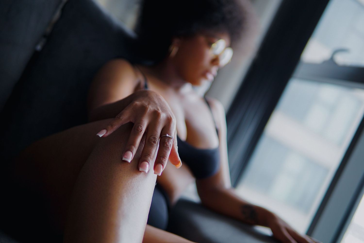 Woman confidently sitting on a sofa looking away, Boudoir photography UK Liverpool