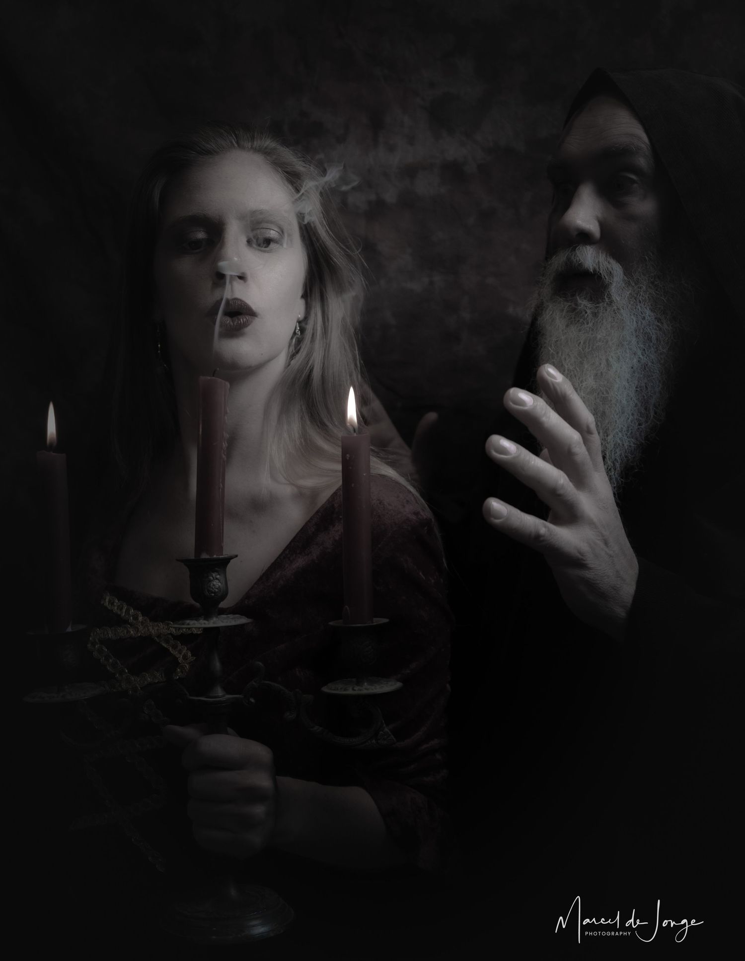 A dark and moody gothic portrait with candlelight illuminating figures against a shadowy background.