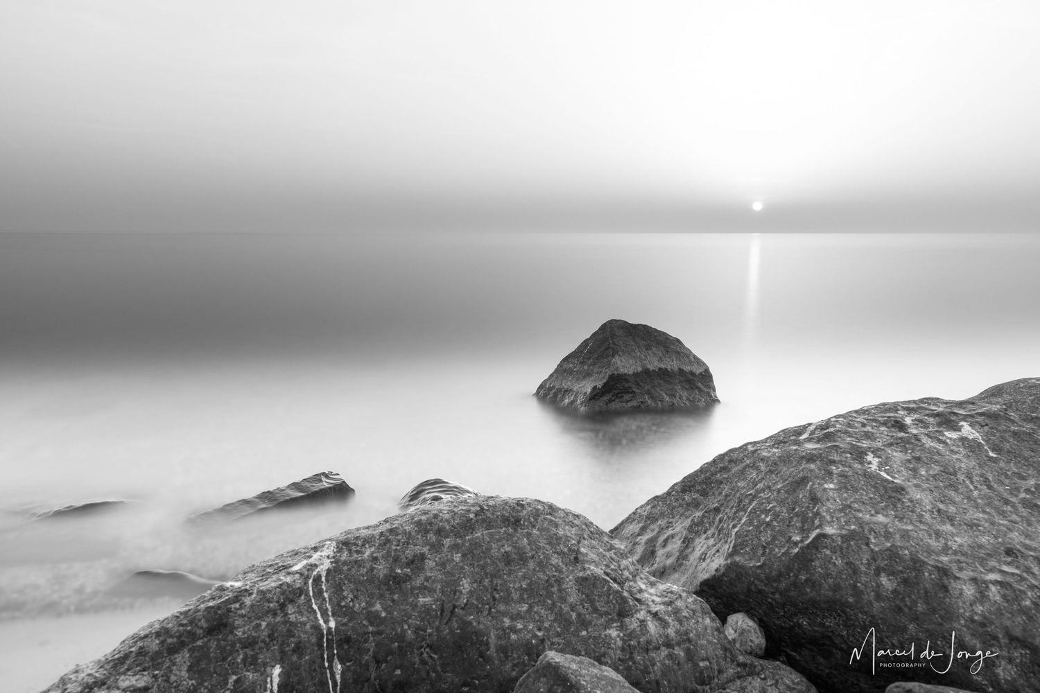 A series of black and white landscape photographs showing misty mountains and coastal scenery in moody lighting.
