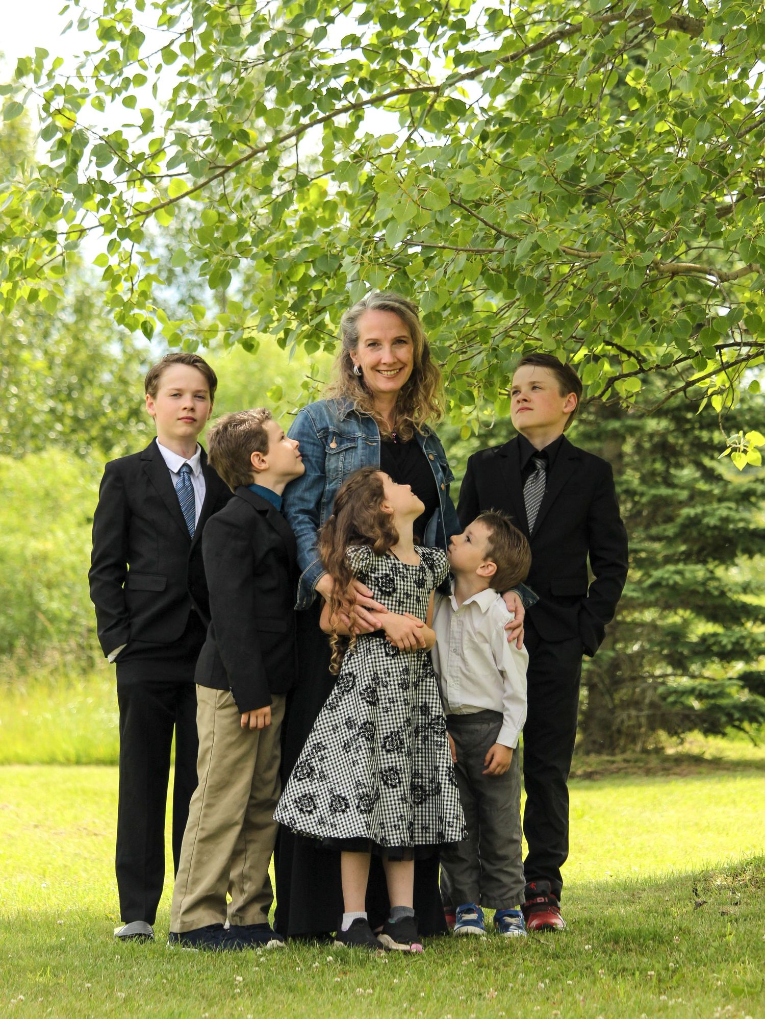 Mom and five children looking at her under tree in Rocky Mountain House, AB
