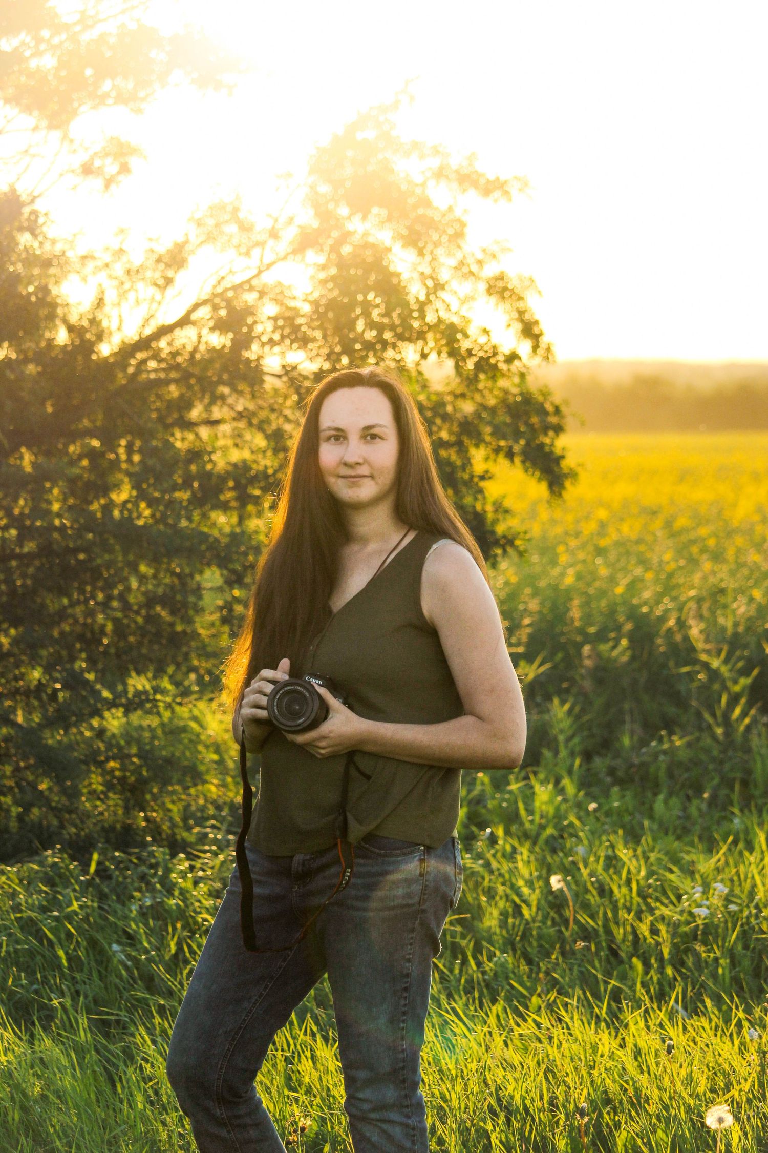 woman holding camera with sun behind at golden hour, Berwyn, AB