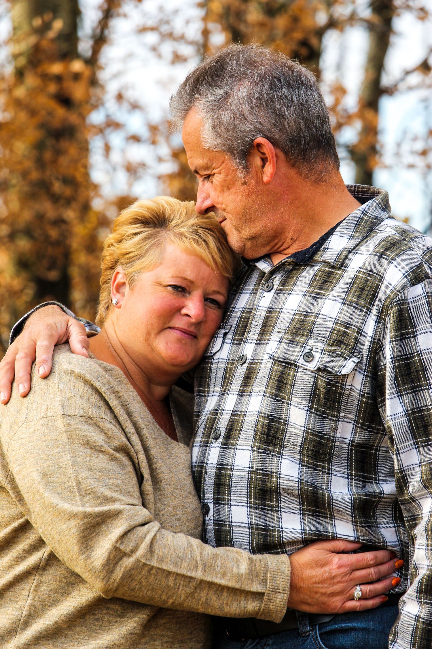 elderly couple hugging with man giving woman a kiss on her forehead in the fall near Peace River, AB