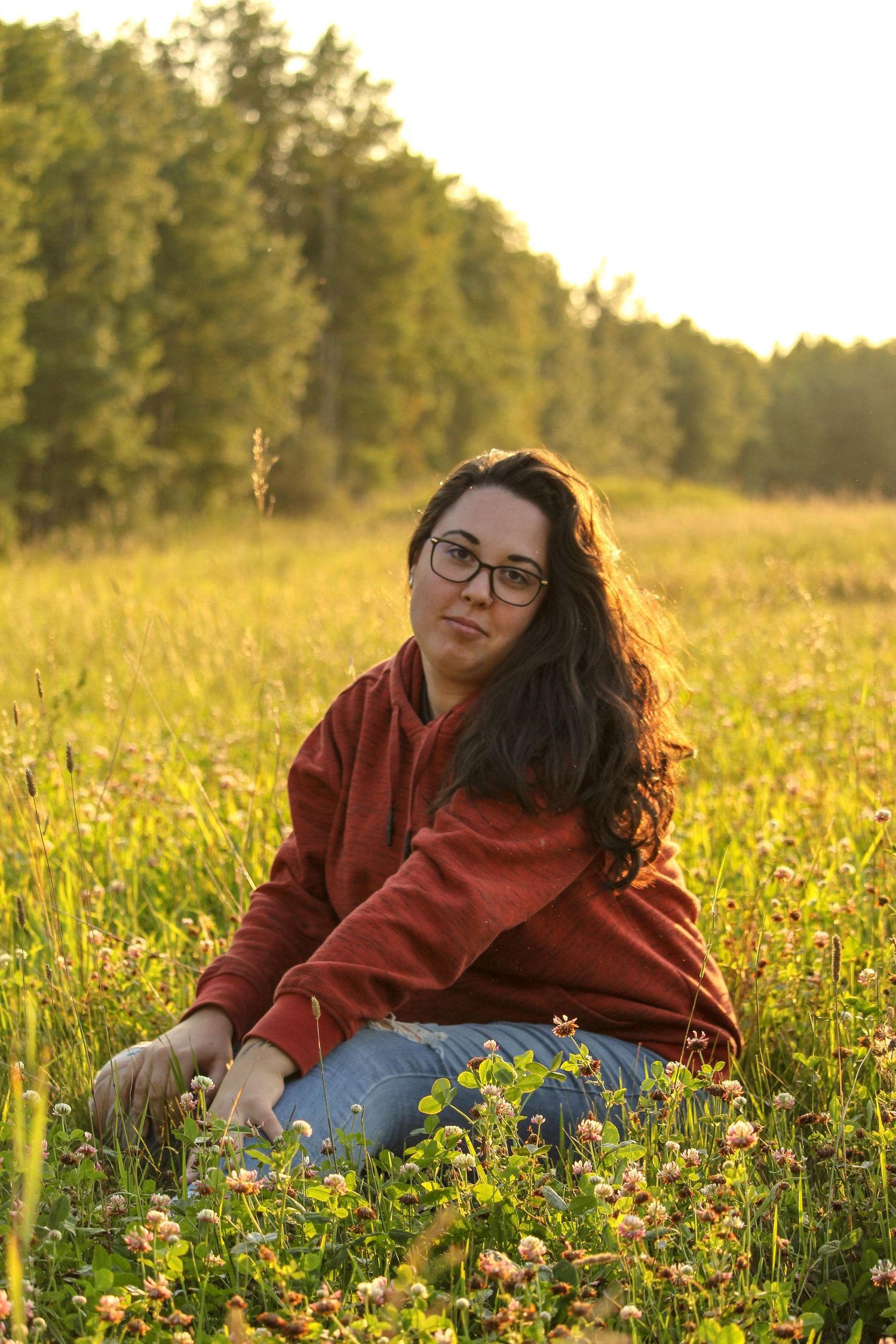 Woman sitting in field near Peace River, AB, golden hour sun behind, summer