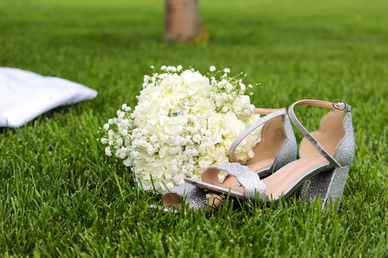 Wedding flat lay with flowers, rings, shoes, grass background with dress in Peace River, AB