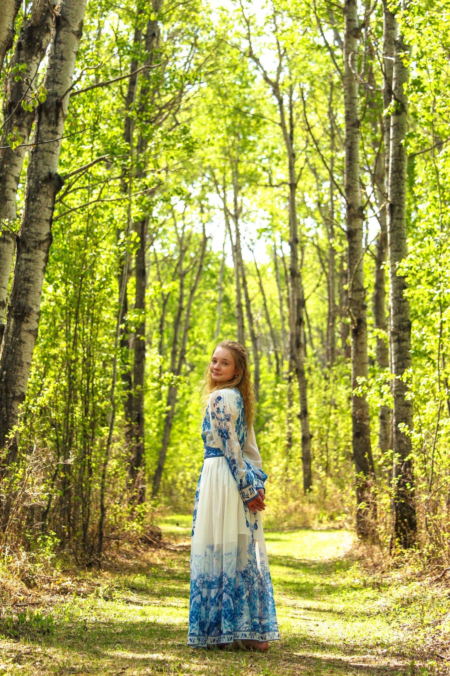 Girl standing looking back down pathway in forest at Lac Cardinal, AB