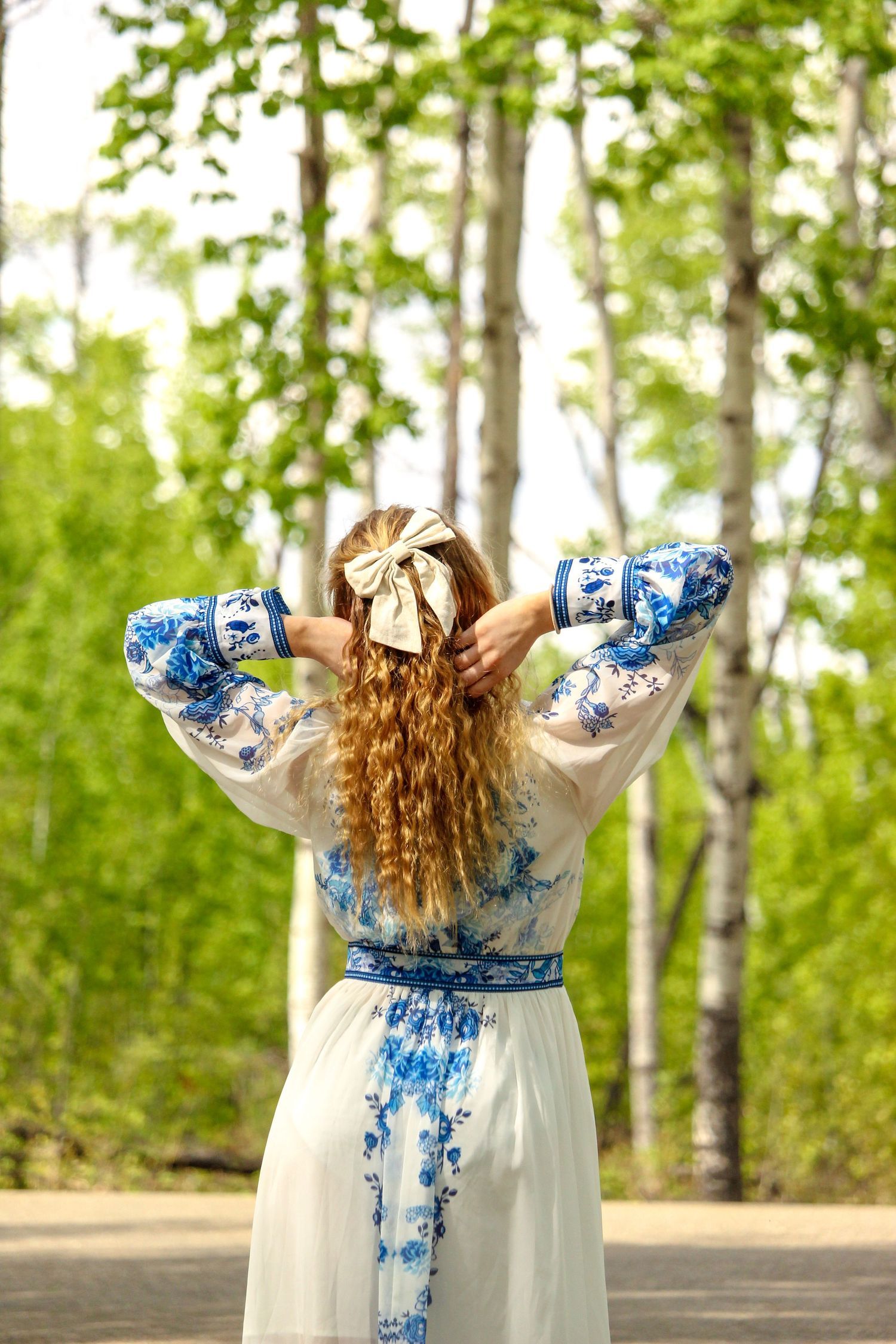 back of girl in dress, hands in hair with bow, summer trees at Lac Cardinal, near Grimshaw, AB