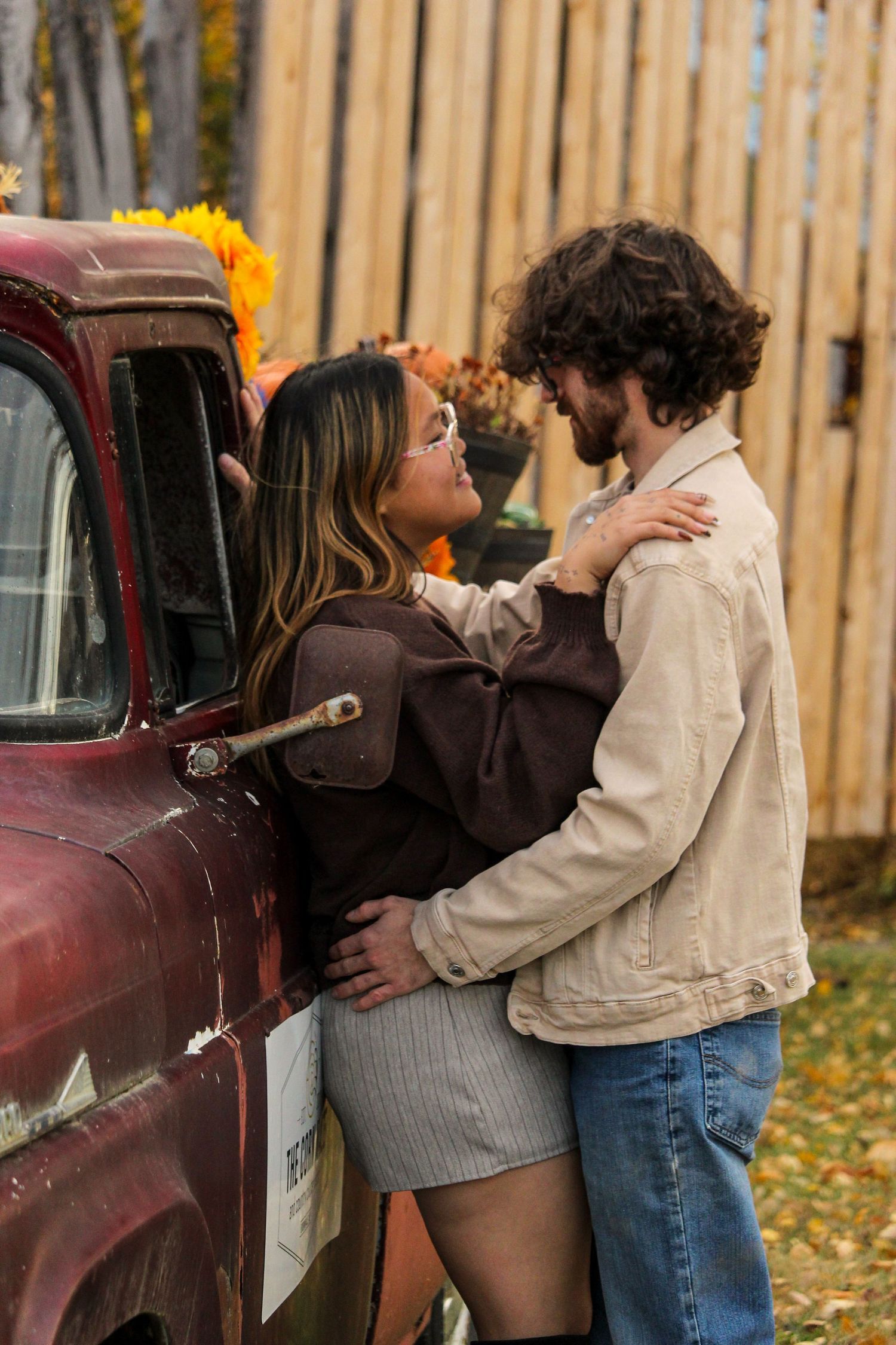 Couple looking at each other and leaning on old truck, fall background near Grimshaw, AB