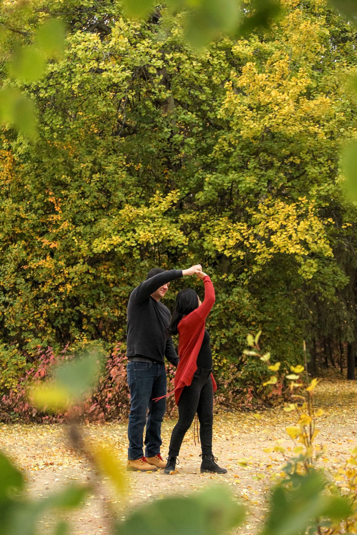 Couple dancing in forest, looking through trees in fall at Lac Cardinal, near Grimshaw, AB