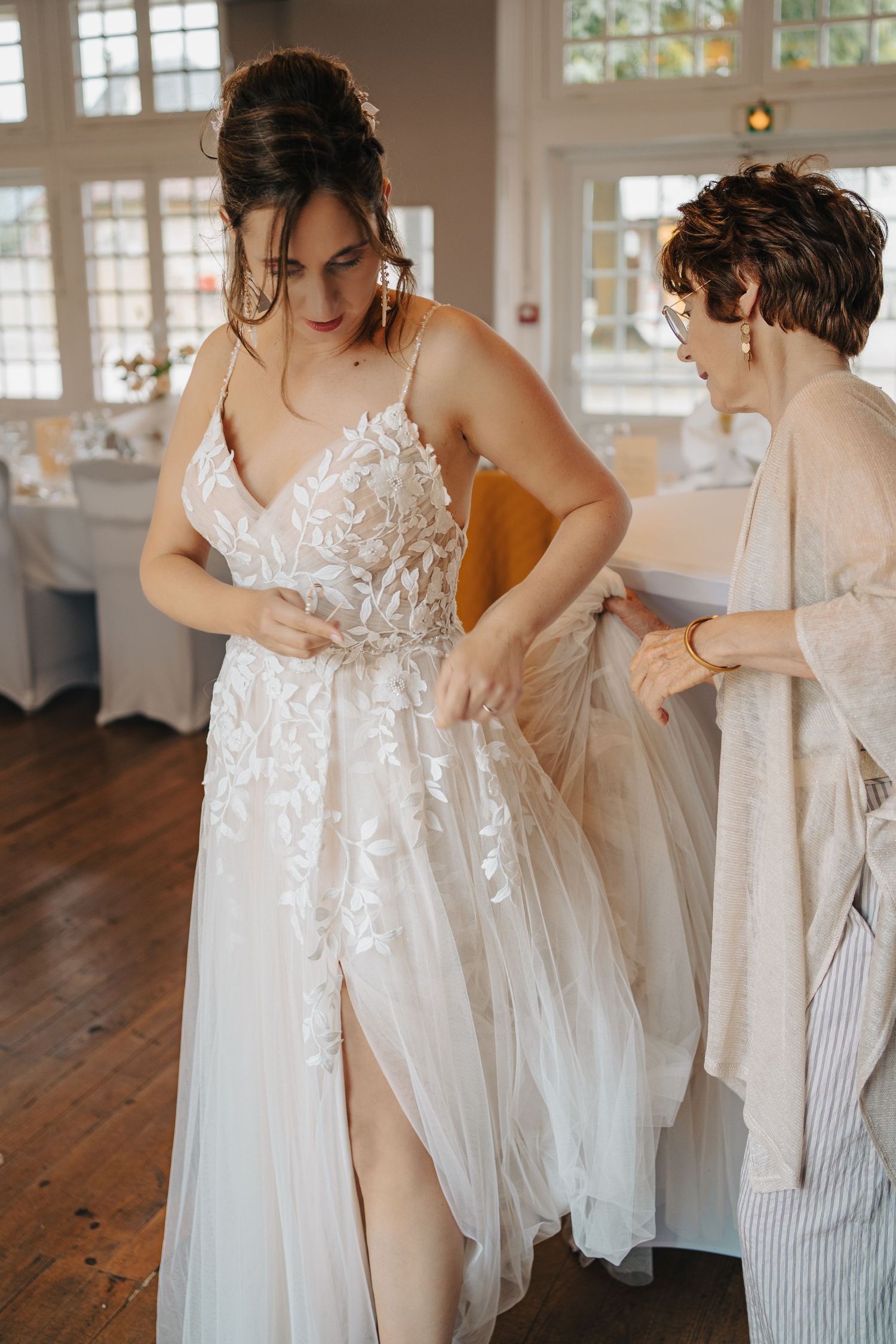 Wedding dress preparation scene in a bright sunlit room with white lace details.