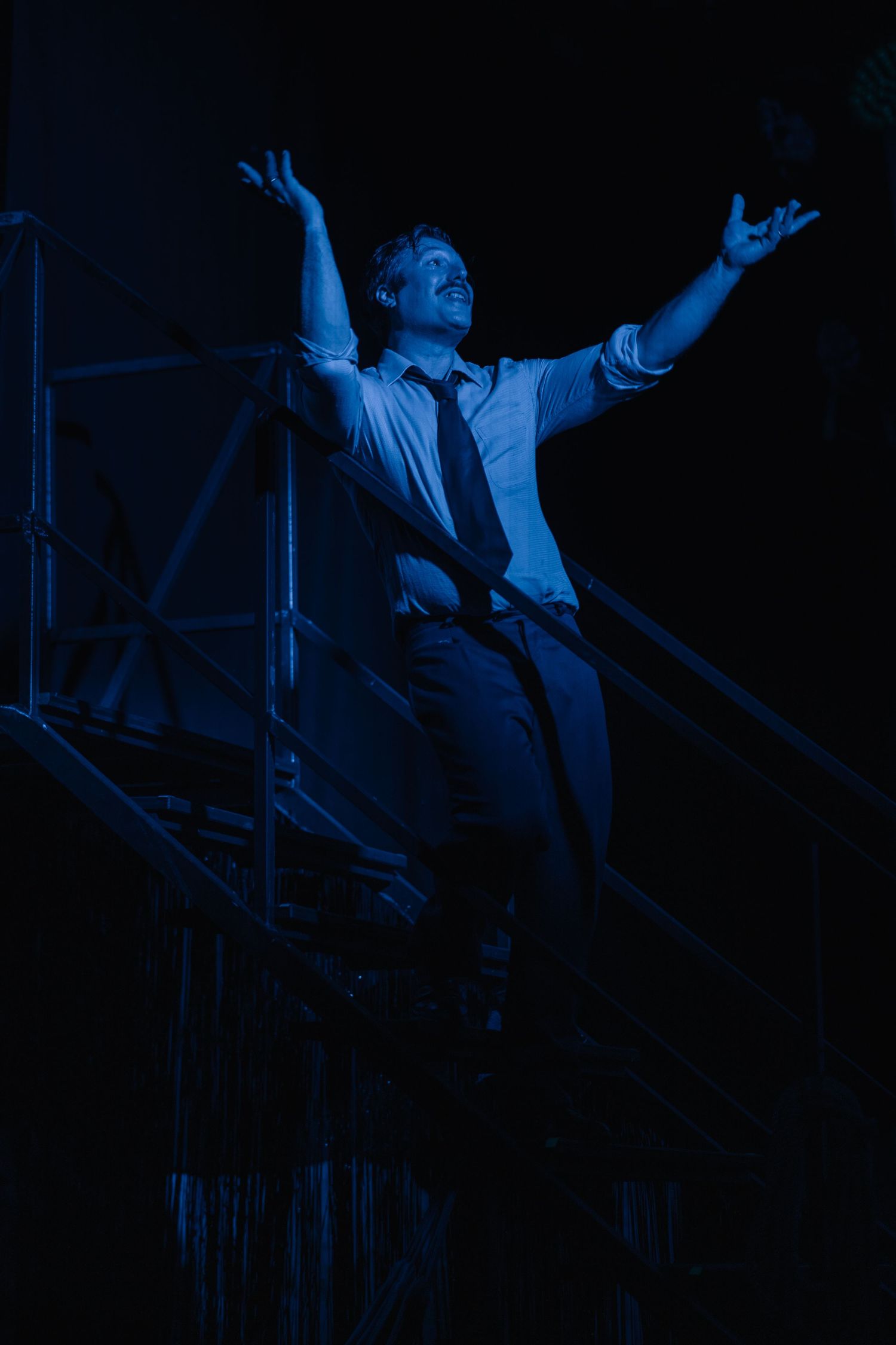 Dramatic silhouettes of performers with arms raised against dark background.
