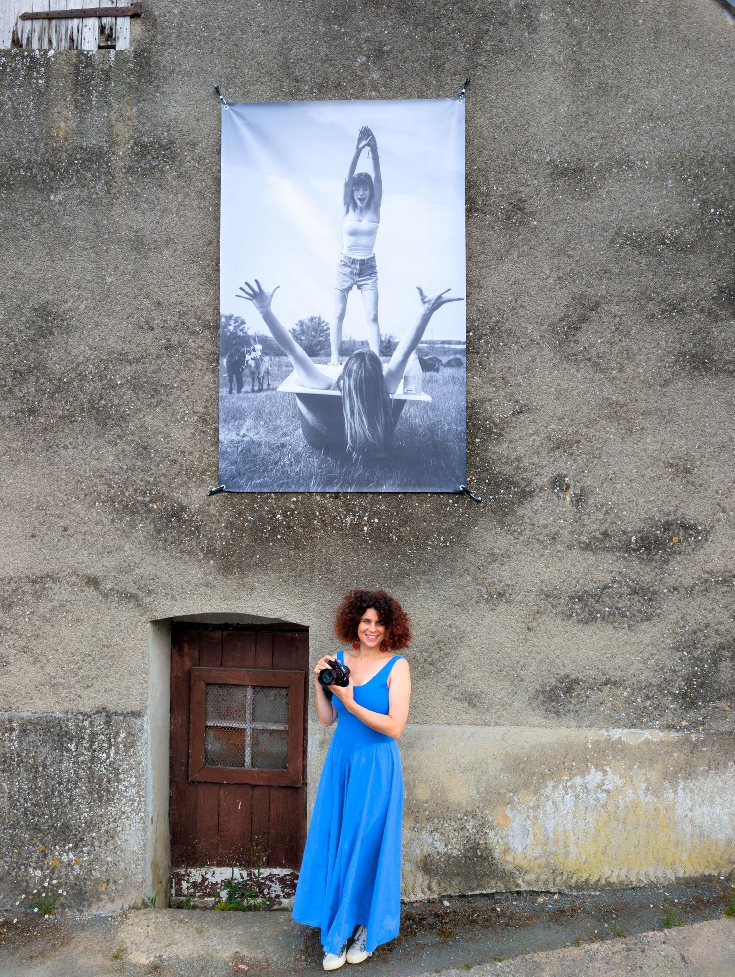 Vintage photographs displayed on concrete wall with blue dress in foreground.