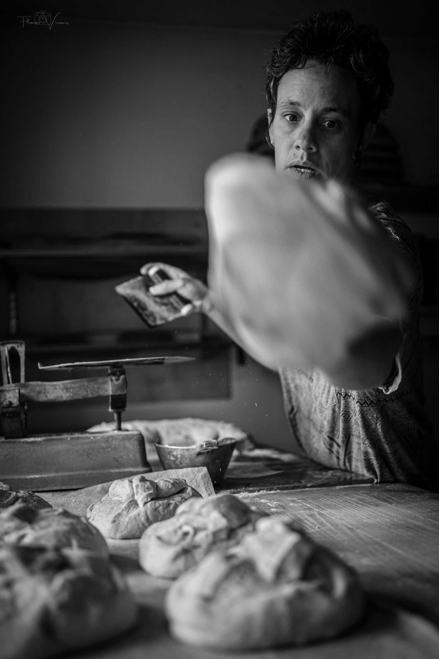 Close-up of bread dough being shaped on a wooden work surface in black and white.