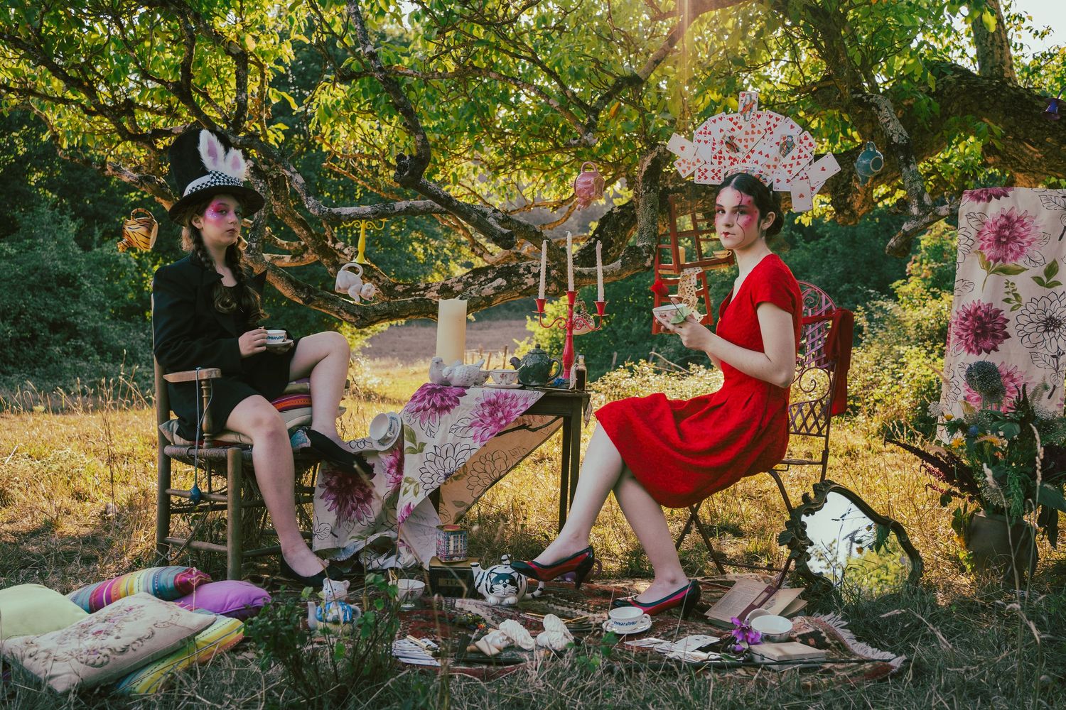 Outdoor tea party setup with pink decorations and floral arrangements in a garden setting.