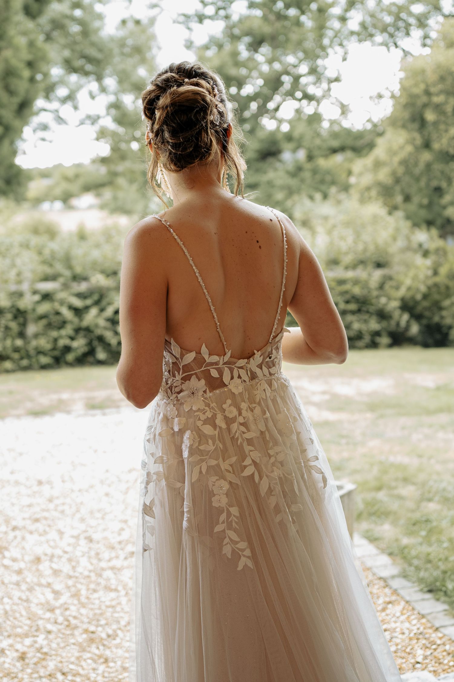 Back view of a delicate lace wedding dress with floral details in natural lighting.