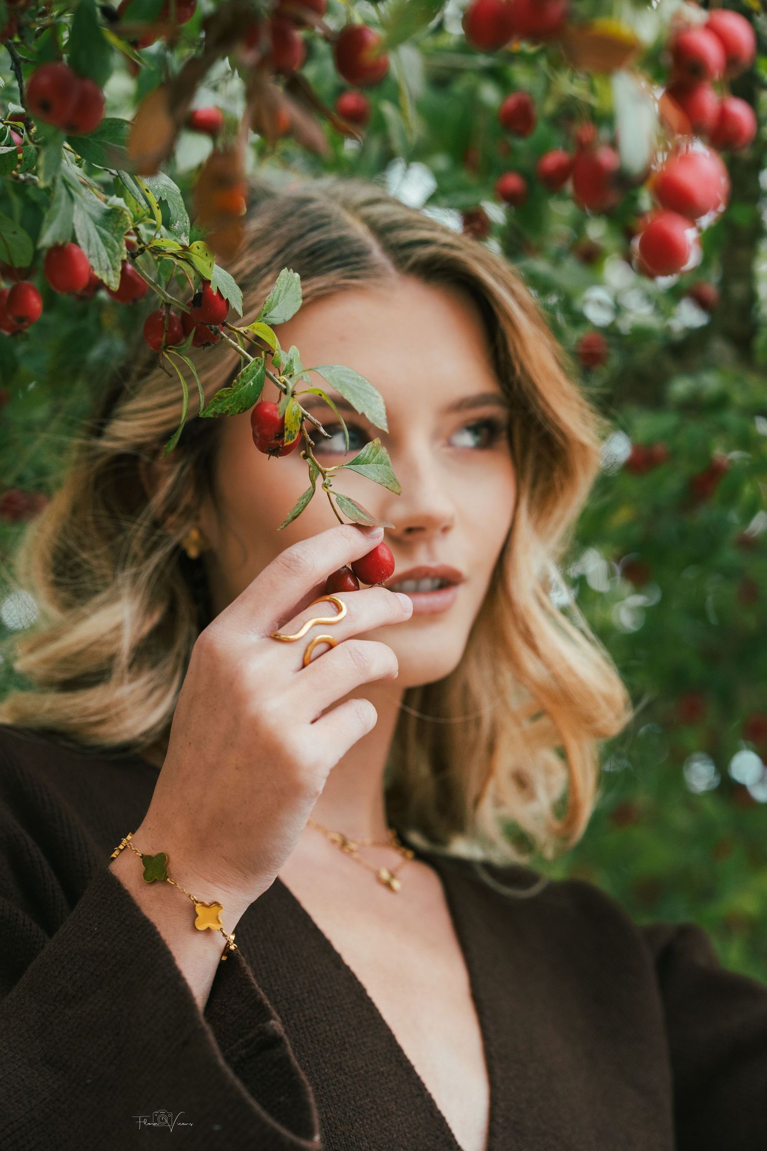 Ethereal portrait among red apple trees with soft natural lighting.