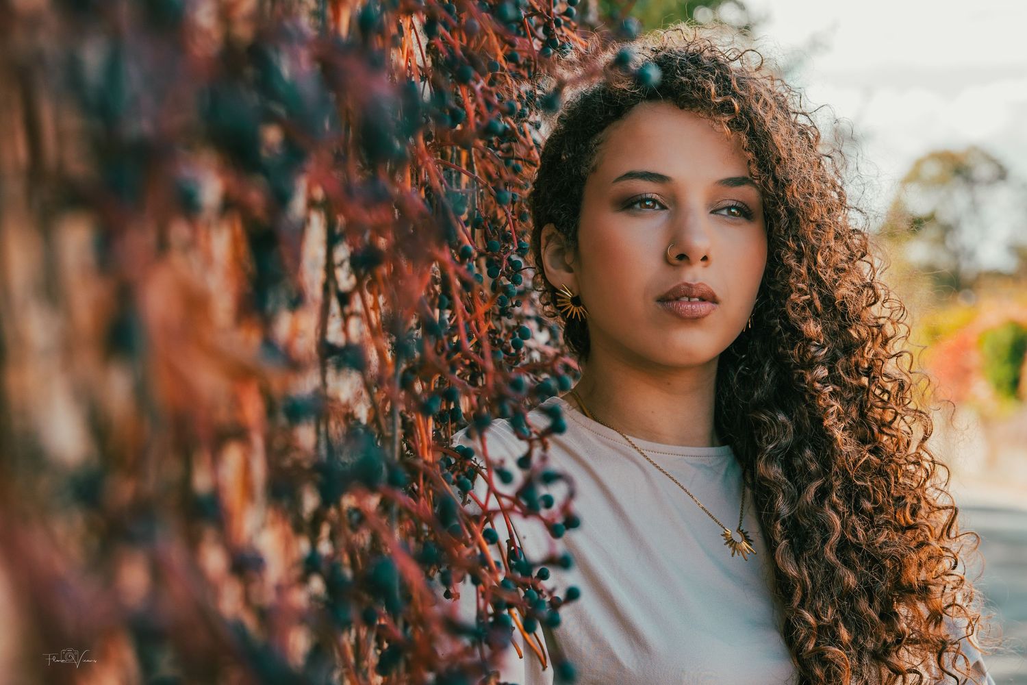 Portrait series against autumn foliage showing natural curly hair and warm lighting.