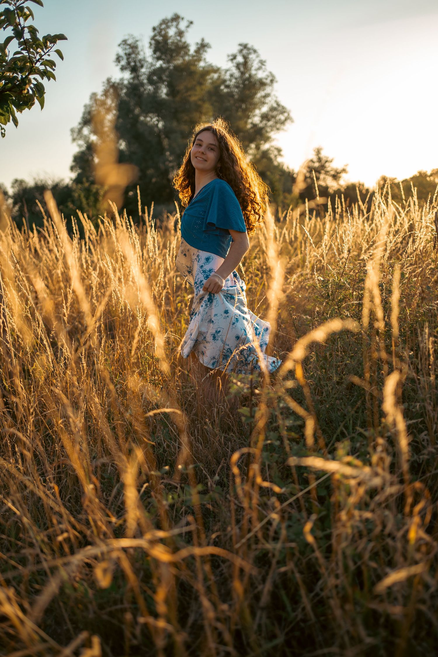Person walking through golden wheat field at sunset with soft natural lighting.