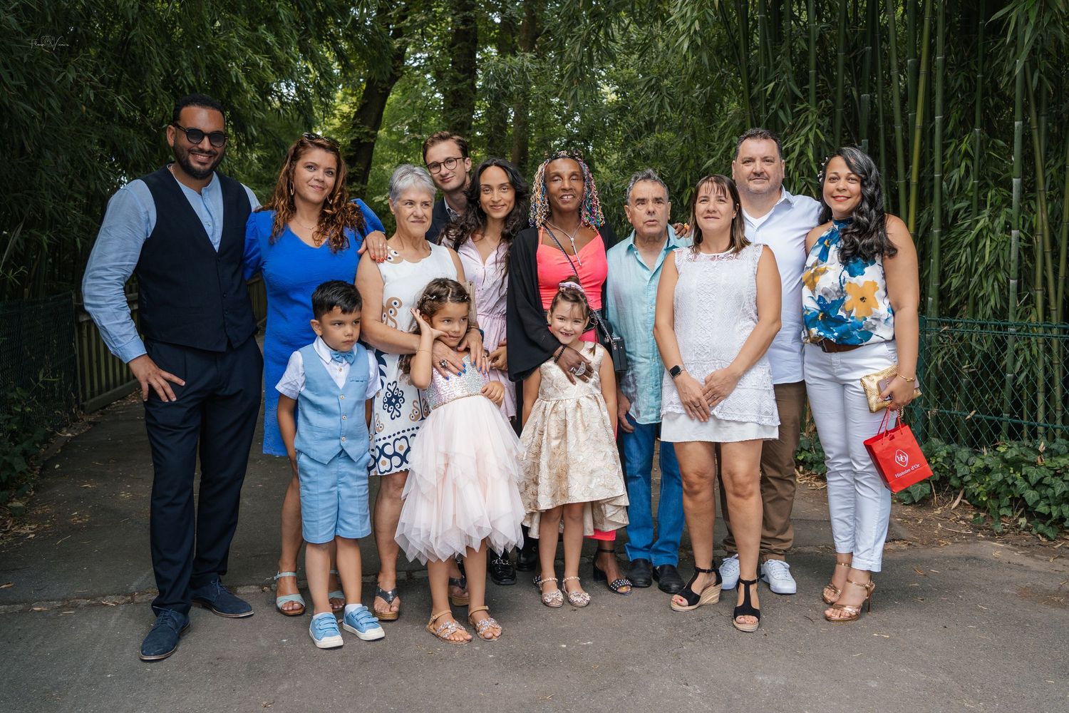 Large group poses together in front of lush bamboo garden backdrop.