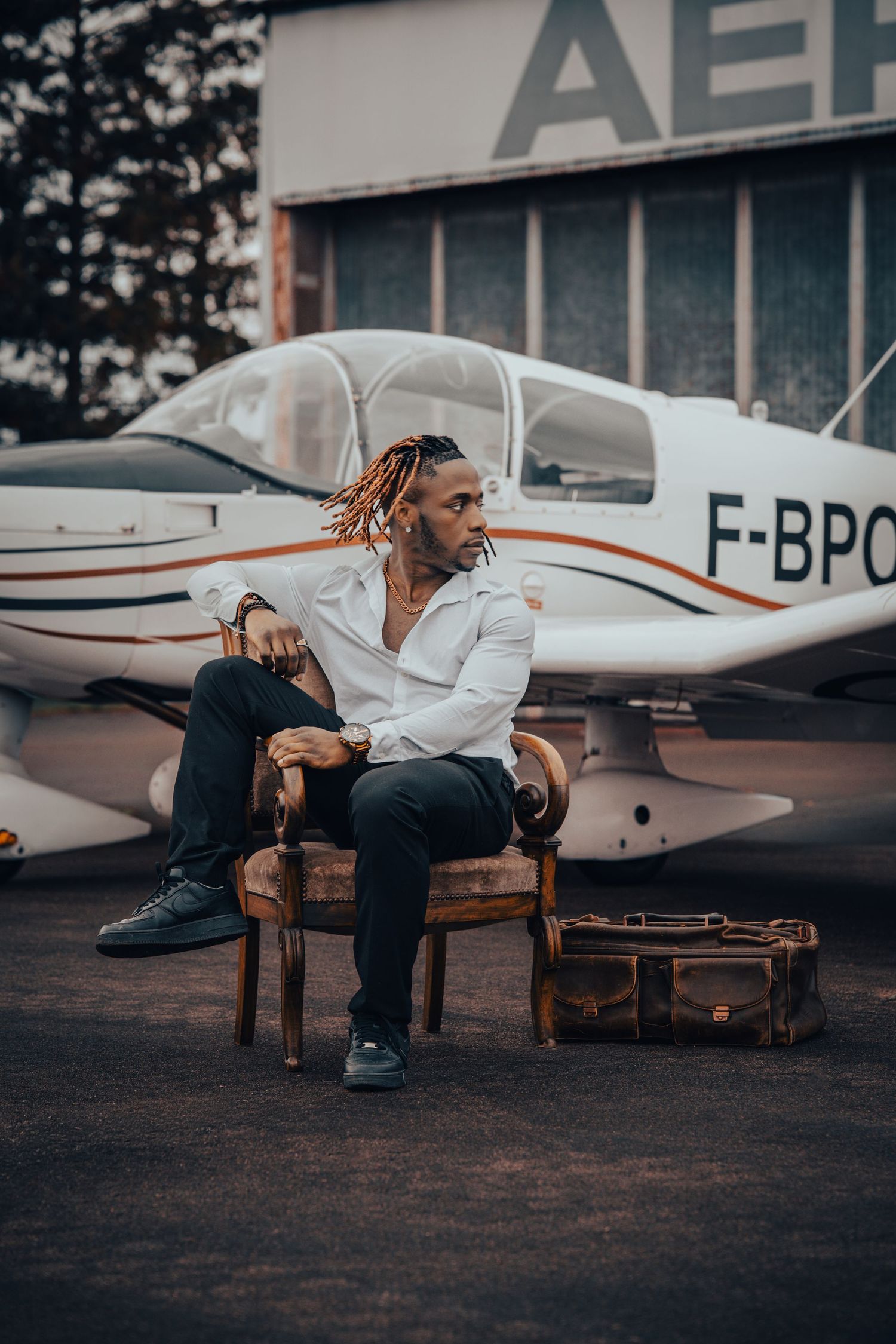 Person in black clothing sits contemplatively near parked aircraft at dusk.