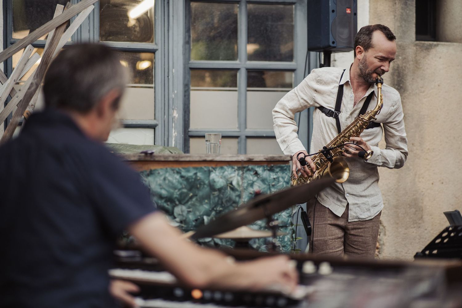 Person playing guitar by a window in muted lighting.