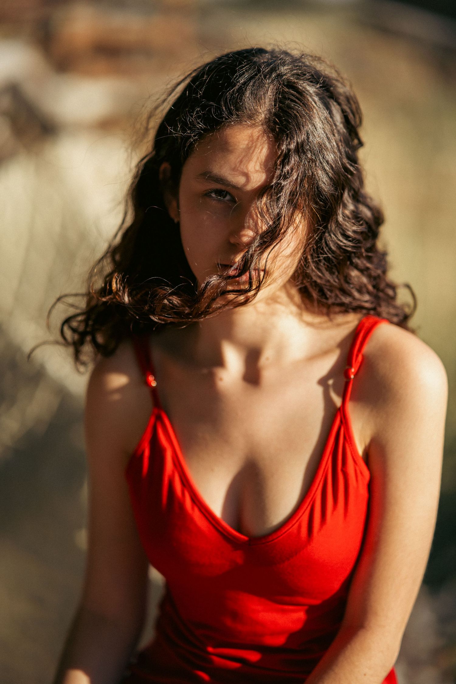 Portrait in red dress with dramatic sunlight and wind-swept hair.