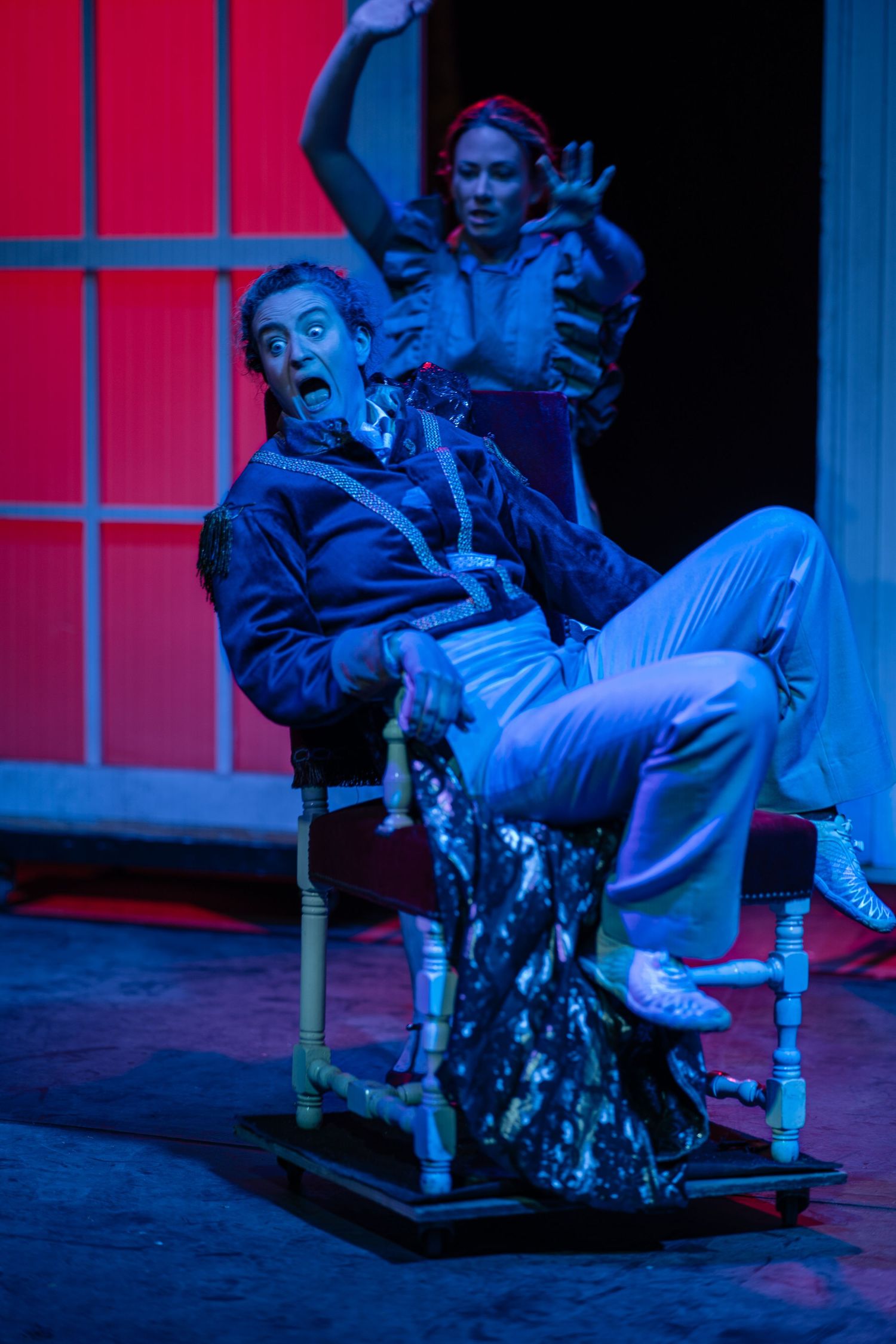 A theatrical performance scene with blue lighting and dramatic poses.