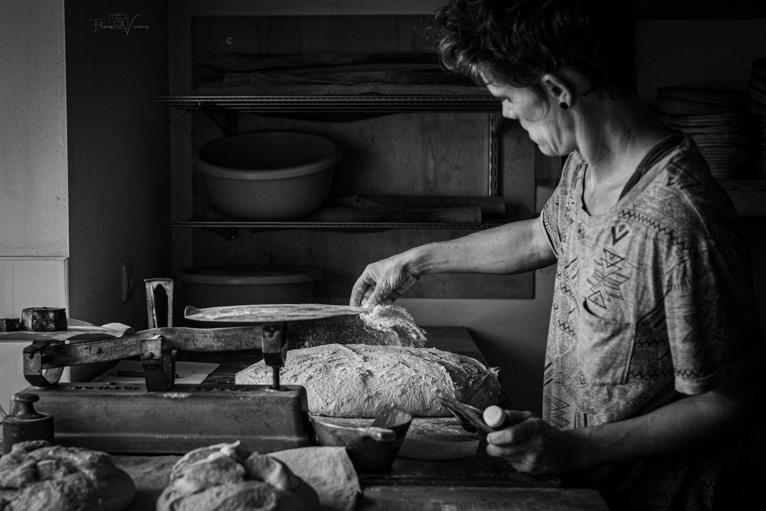 Artisanal baker working with flour and dough in a rustic bakery kitchen.